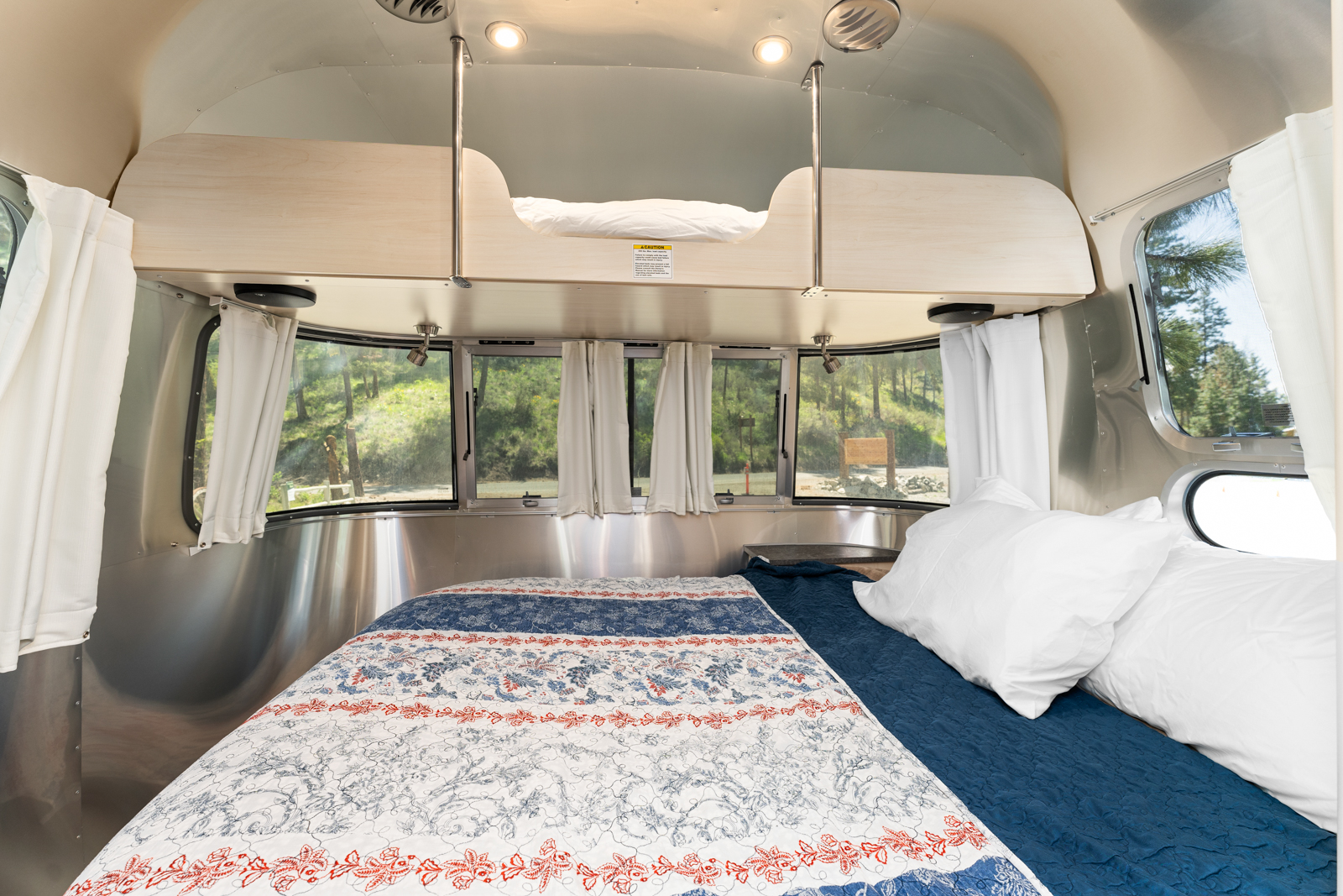 Cozy Airstream RV rental bedroom with lower bed and bunk, ideal for travelers seeking comfortable accommodations amidst nature.. Airstream Flying Cloud 2023
