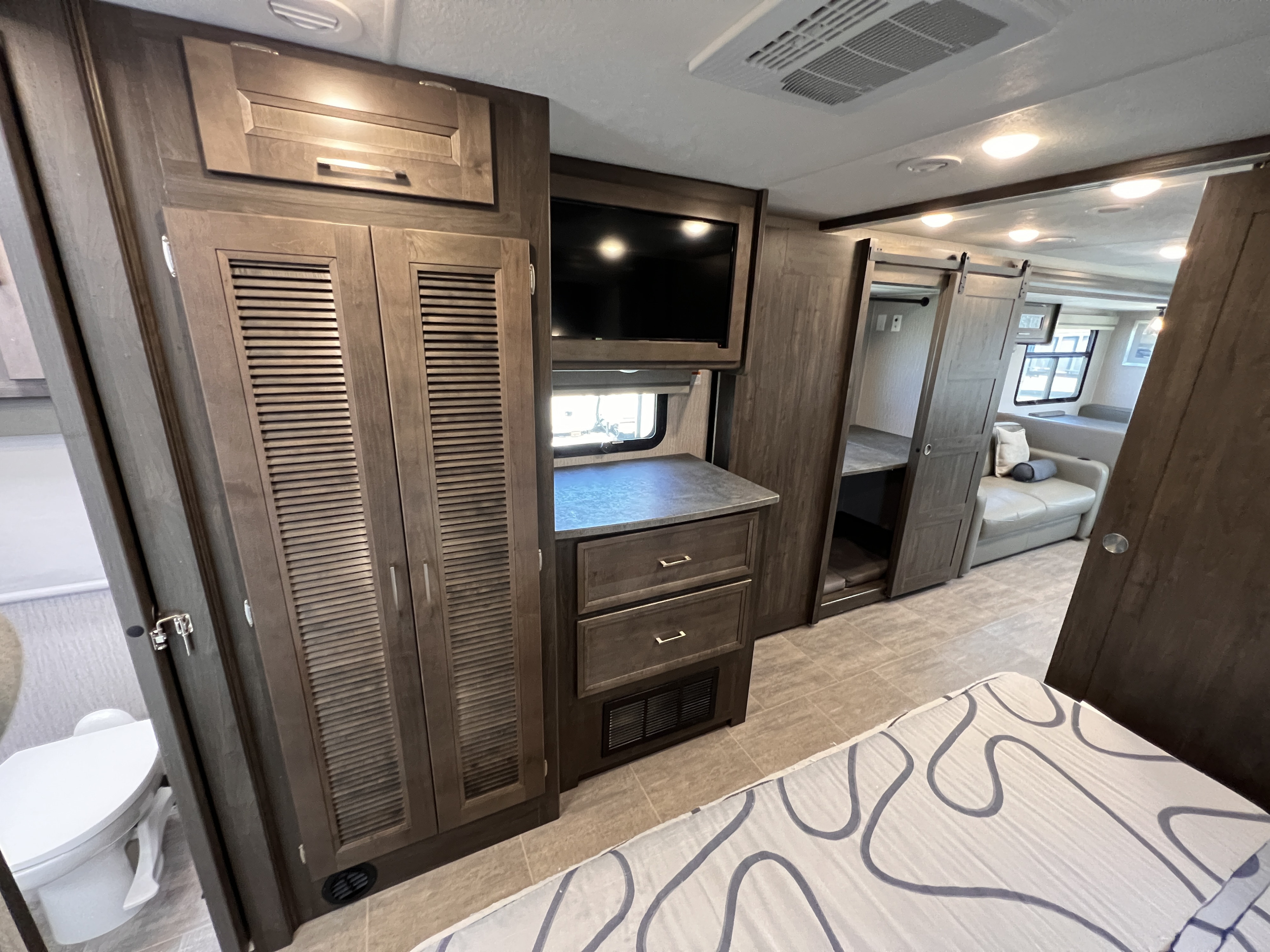 Modern RV rental bedroom with clever storage, TV, and sliding doors to the living area. Comfort for your travels.. Coachmen Mirada 2022