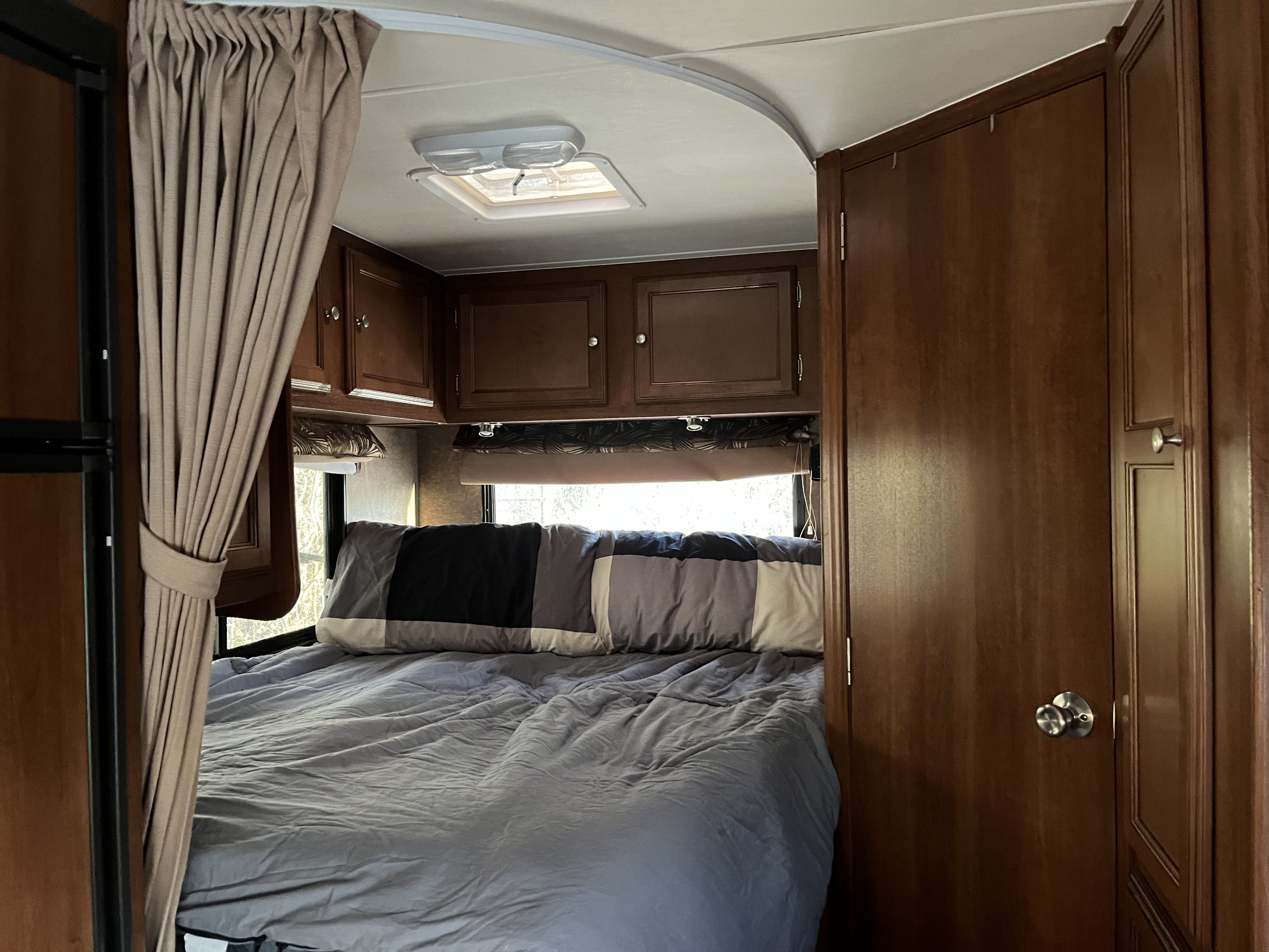 Cozy RV rental bedroom with a comfortable bed, overhead storage, and natural light from the window.. Coachmen Leprechaun 2014