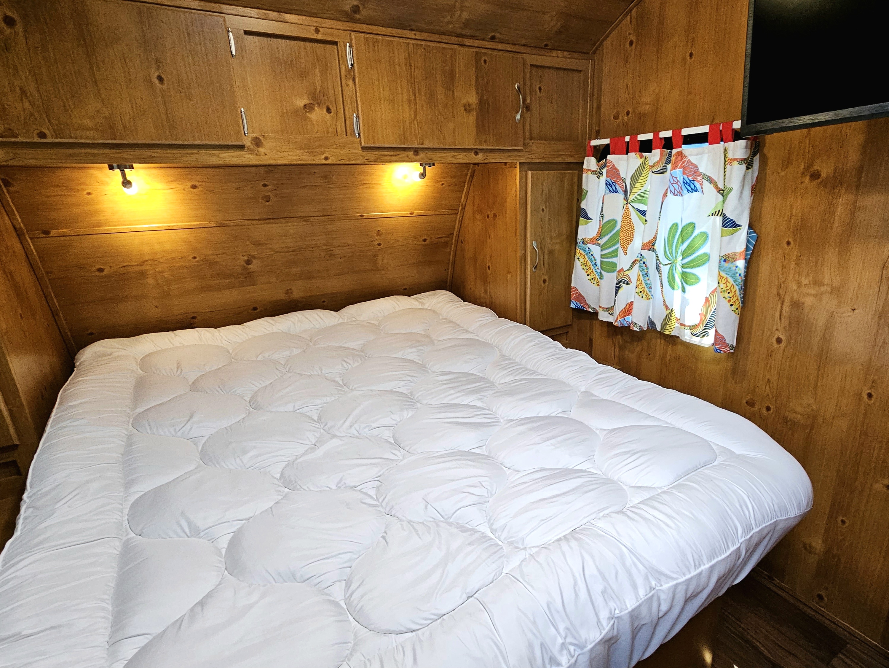 Cozy RV rental bedroom with a soft white bed, warm wood walls, and practical storage.. Gulf Stream Vintage Cruiser 2023