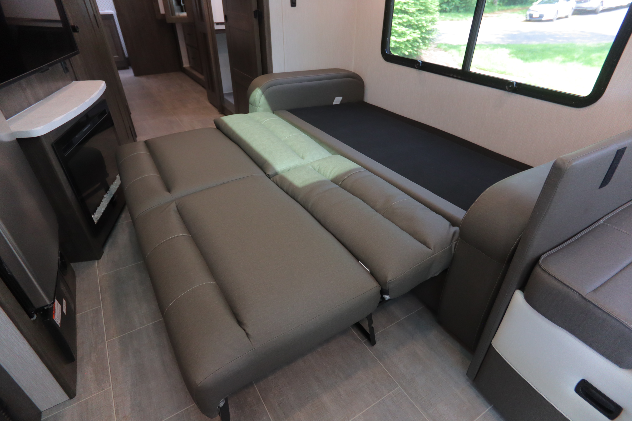 RV rental: Grey sofa bed partially extended, showcasing its easy conversion from seating to comfortable sleeping space.. Coachmen Encore 2024