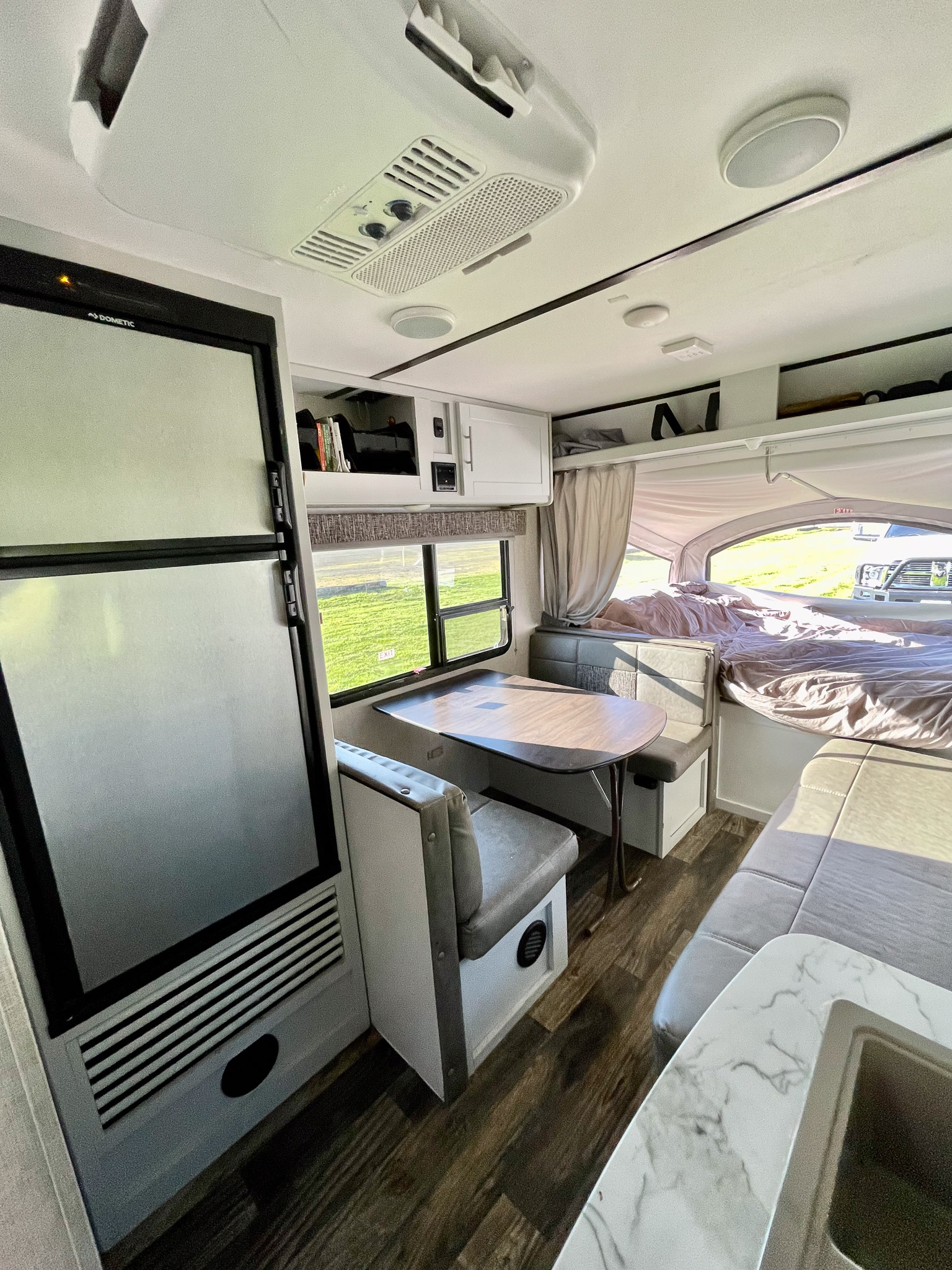 Interior of an RV rental: Compact living space with a dinette, refrigerator, and a pop-out bed area. Ideal for travel.. Keystone RV Bullet Crossfire 2019