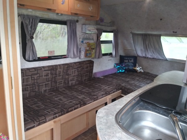 Inside a functional RV rental: cozy seating converts to a bed, with a compact kitchen and storage for comfortable travel.. Prolite Prolite Trailer 2014