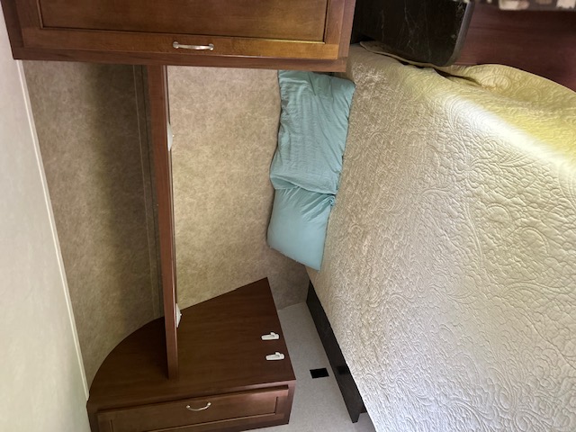 Experience a comfortable RV rental bedroom with a neatly made bed, light-colored patterned bedding, and wooden storage units.. Jayco Jay Flight SLX 2017