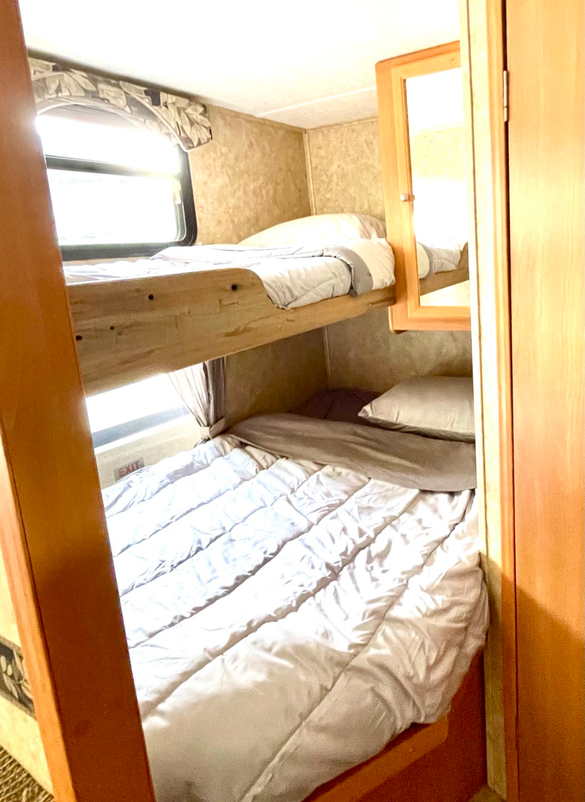 RV rental interior with cozy bunk beds: two compact beds with clean bedding, bright windows, and an emergency exit.. RTFLY CCH 2007