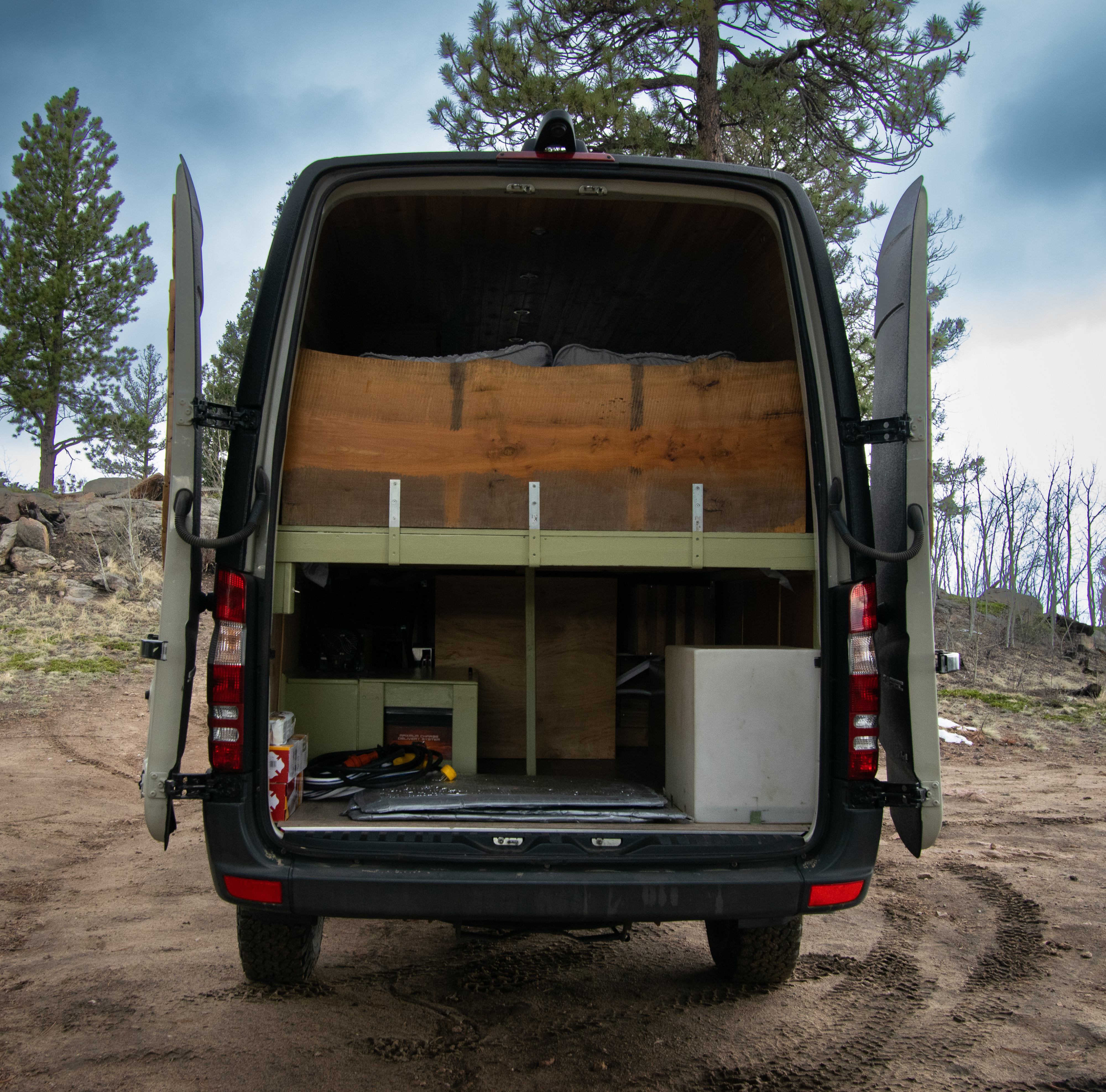 RV rental van's open rear reveals custom bed platform & storage, ideal for off-grid adventures.. Mercedes-Benz Sprinter 2500 2016