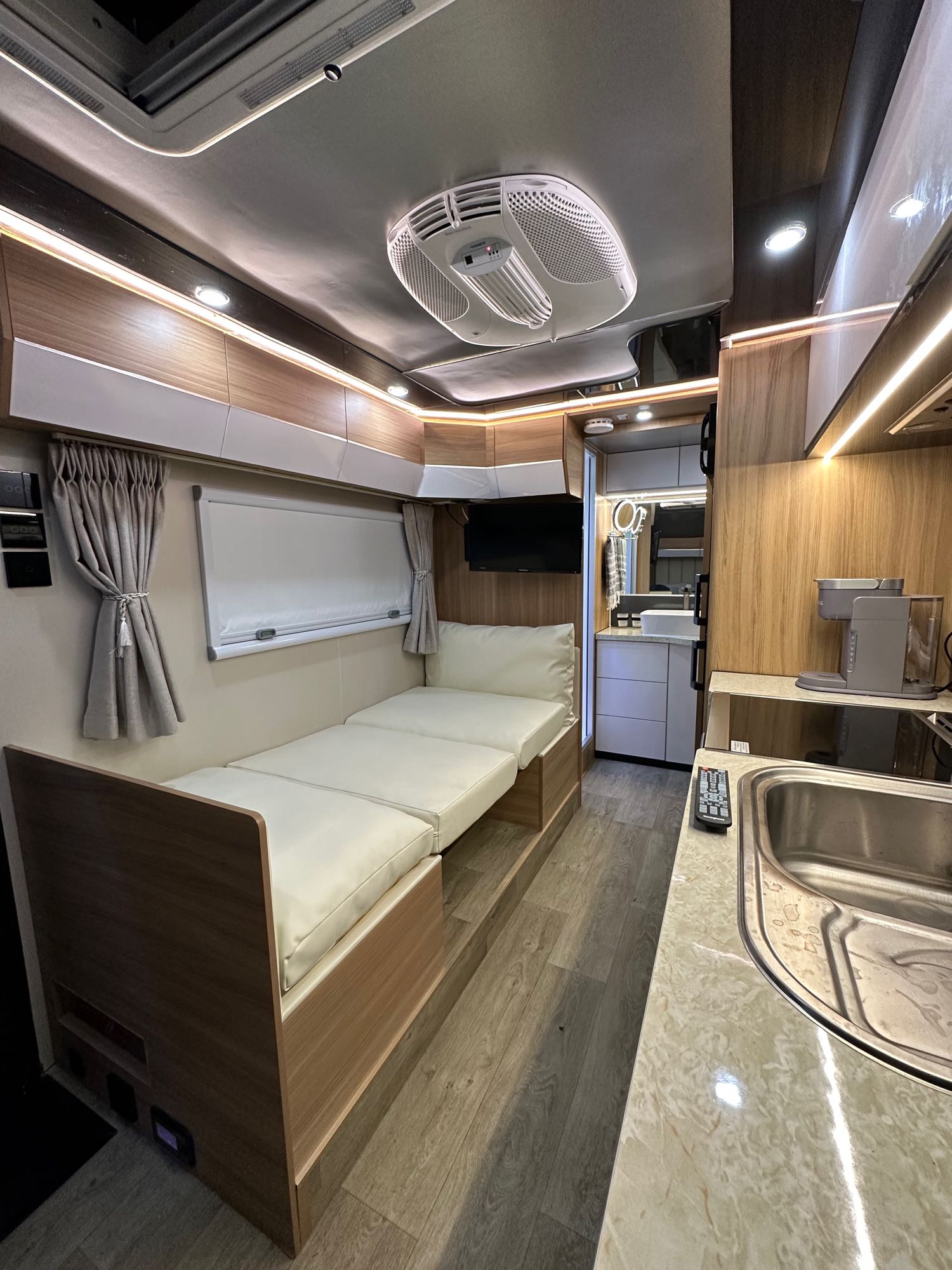 Inside a stylish rv rental: a cozy bed, compact kitchen with sink, and modern wood finishes for travel comfort.. Black Series Black Series Trailer 2022