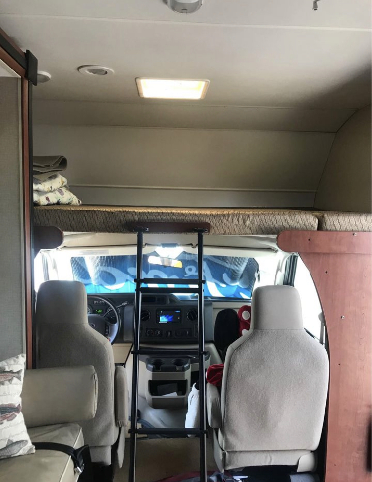 RV rental interior: Overhead bunk with ladder, front cab, and seating area for comfortable travel.. Winnebago Minnie Winnie 2014