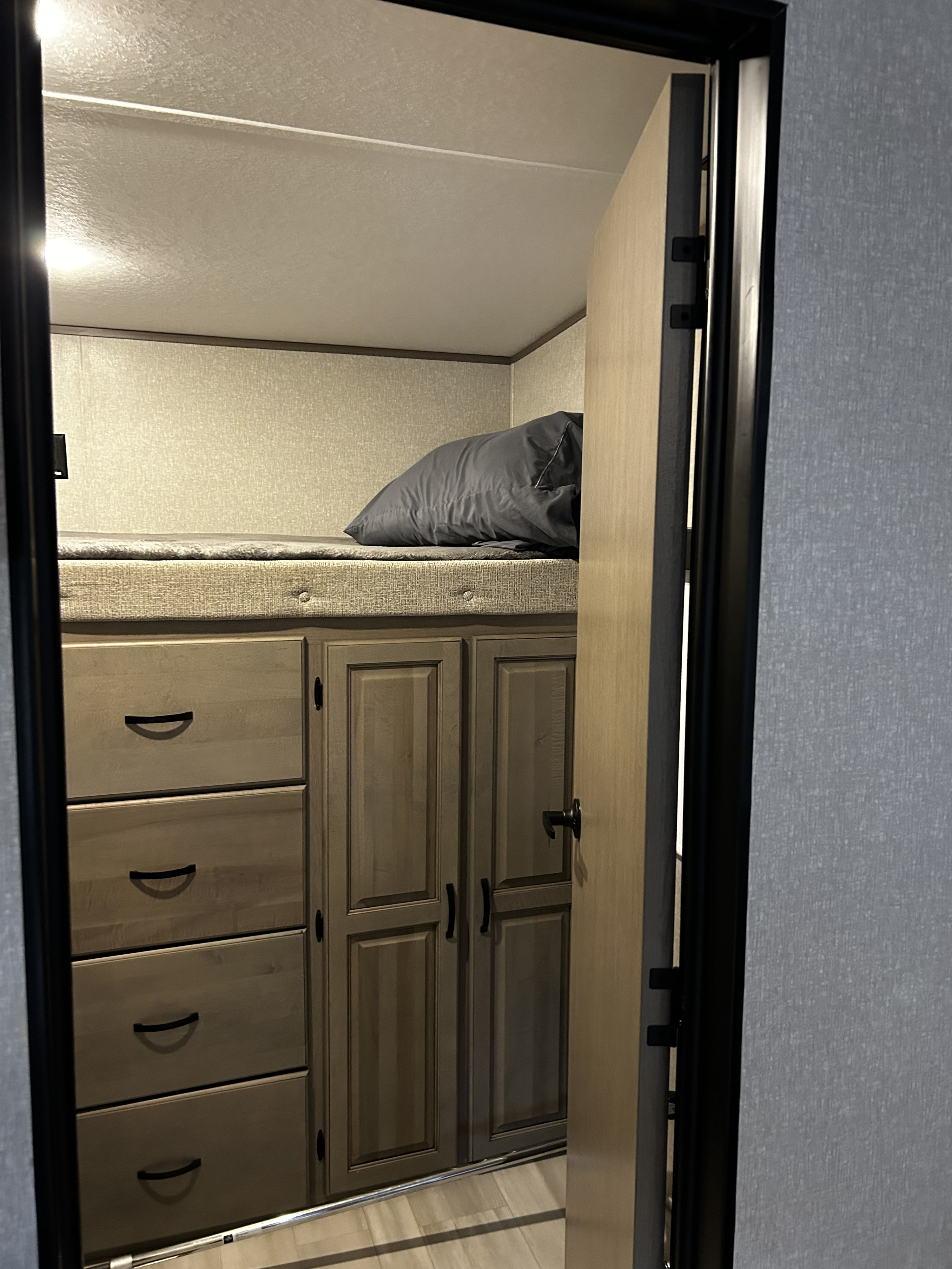 Cozy RV rental bunk bed setup with built-in storage drawers and cabinets, perfect for compact travel lodging.. Coachmen Chaparral 2022