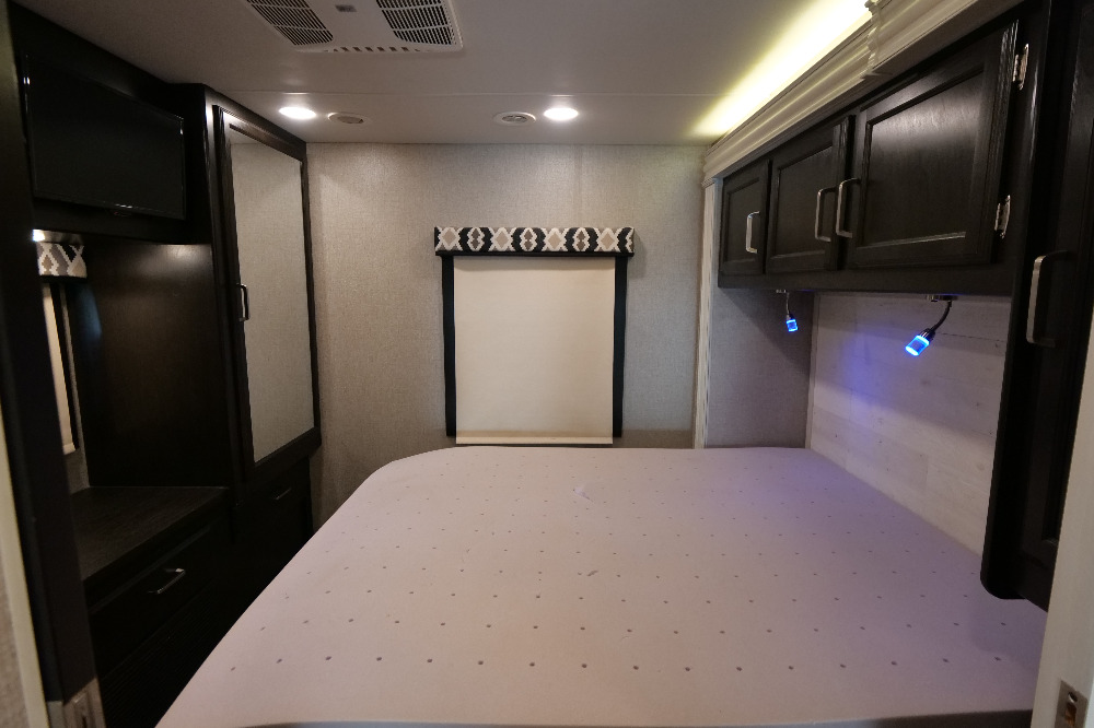 RV rental bedroom: comfortable bed, TV, mirrored wardrobe, window, overhead storage, and blue lights.. Jayco Greyhawk 2021