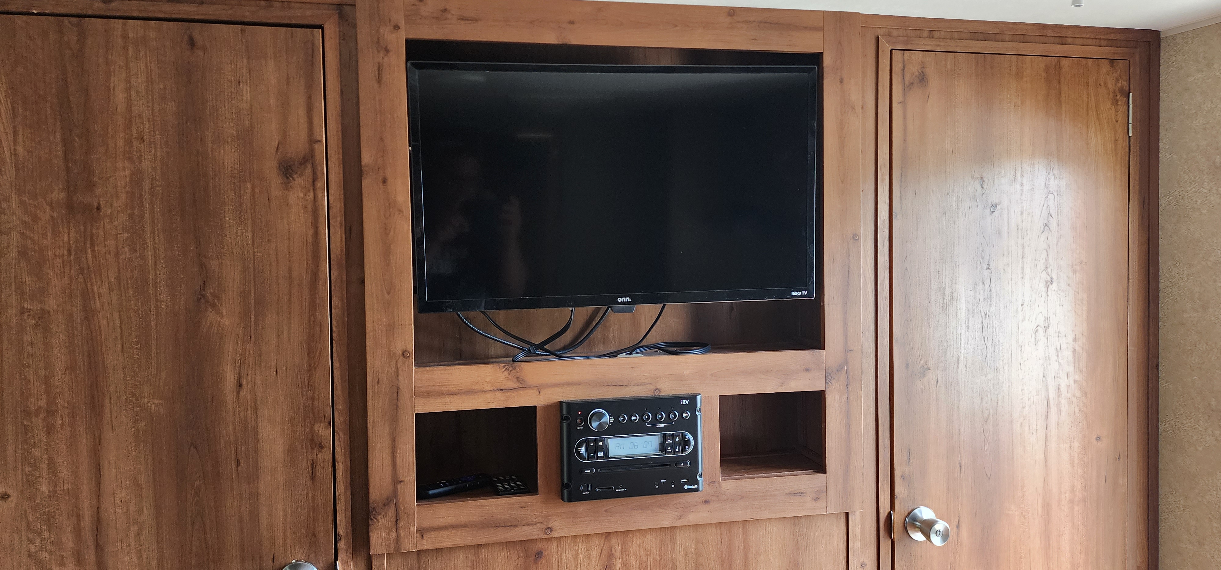 RV rental living space featuring a mounted TV, integrated audio system, and ample wooden storage cabinets.. Gulf Stream Ameri-Lite 2017