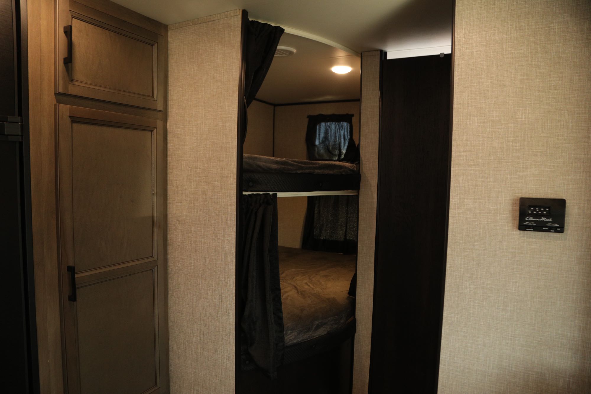 Inside an RV rental: a neat bunkhouse with two beds, privacy curtains, and ample storage cabinets.. Jayco Jay Flight 2023