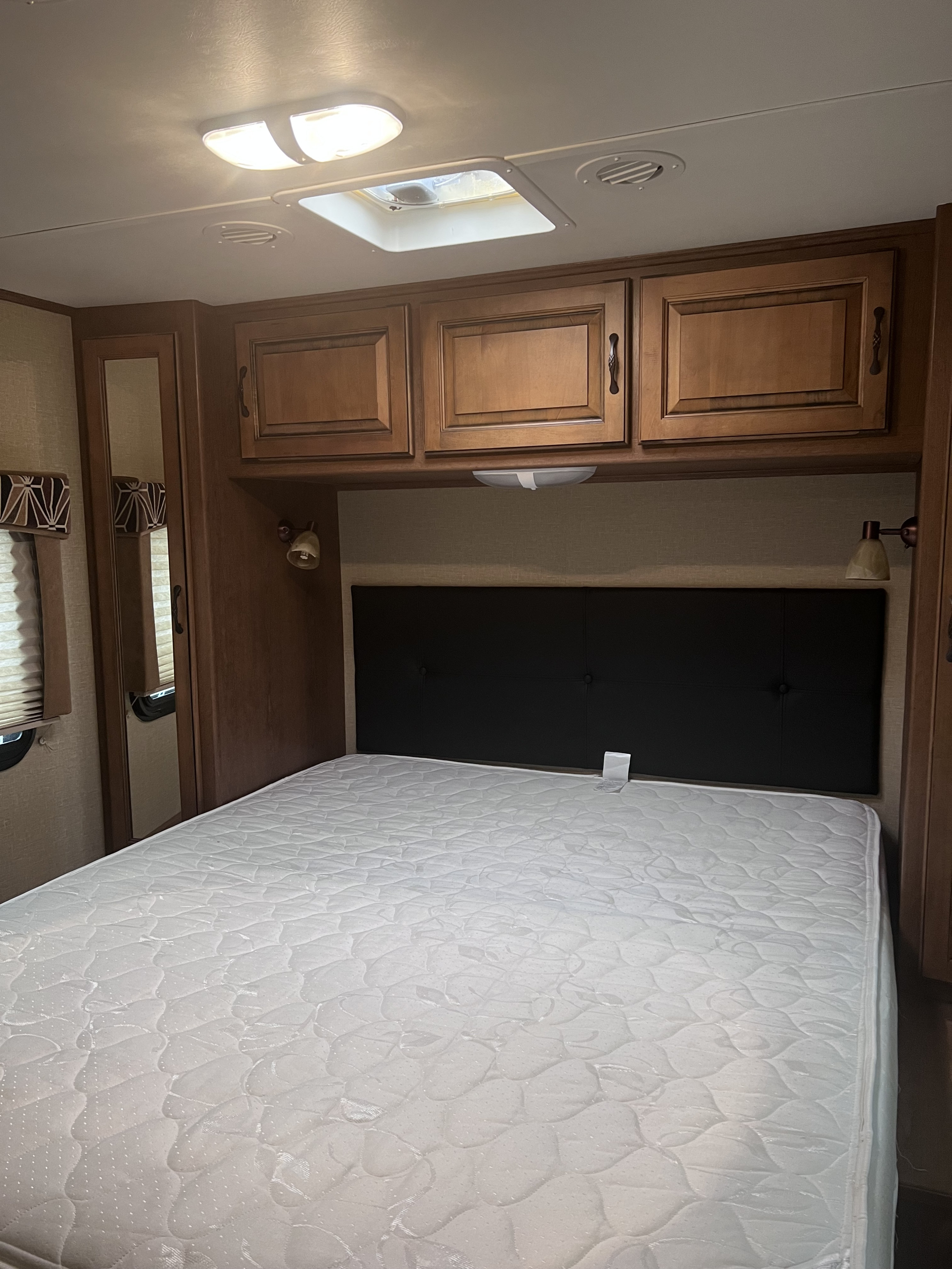 RV rental bedroom: clean mattress, black headboard, wood cabinets & mirror. Ceiling lights & vent for comfort.. Cruiser RV Viewfinder Signature 2014
