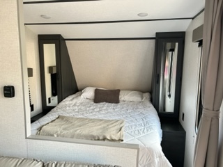 Explore this RV rental bedroom: a cozy bed with crisp white bedding, flanked by mirrored wardrobes. Great for camping trips.. Dutchmen Aspen Trail LE 2022
