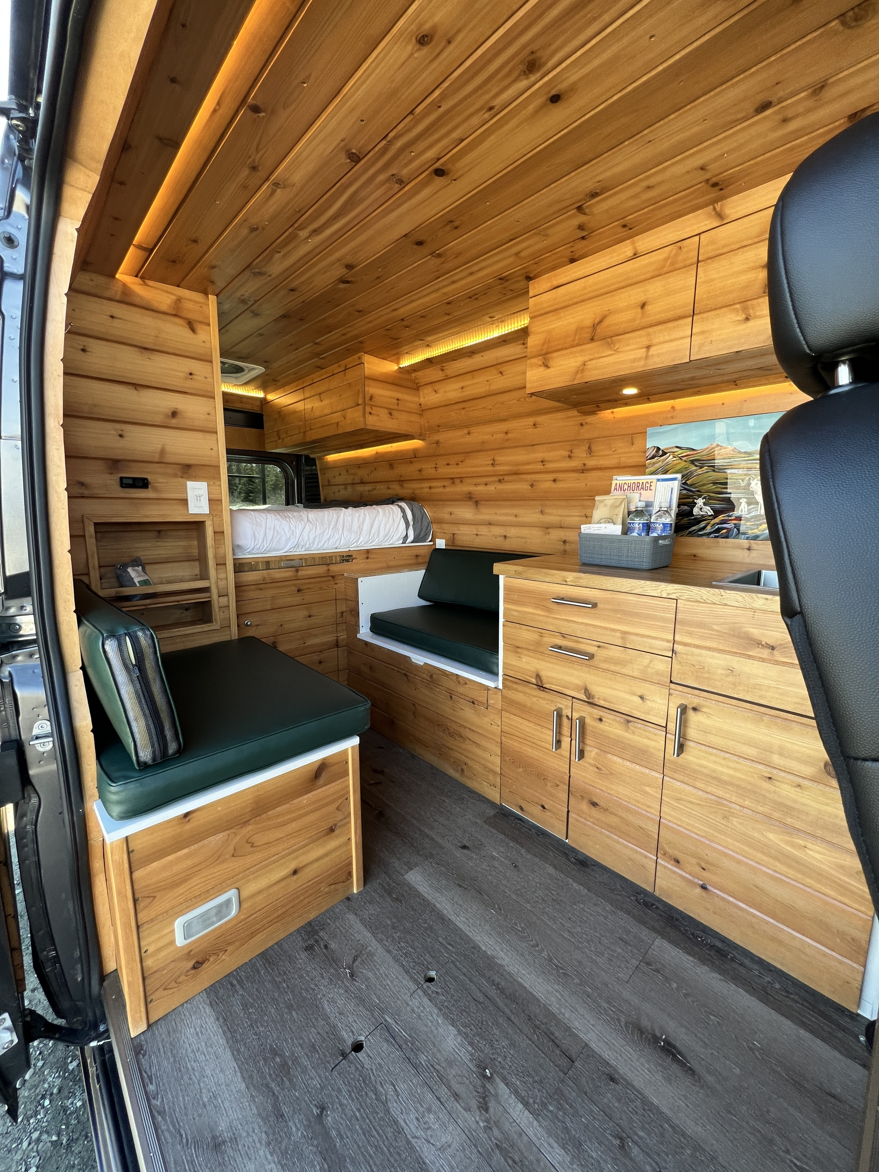 Explore this warm, wood-paneled RV rental interior, featuring a cozy bed, seating, and kitchen for your mobile adventures.. Dodge Ram 2500 (Class B) 2021