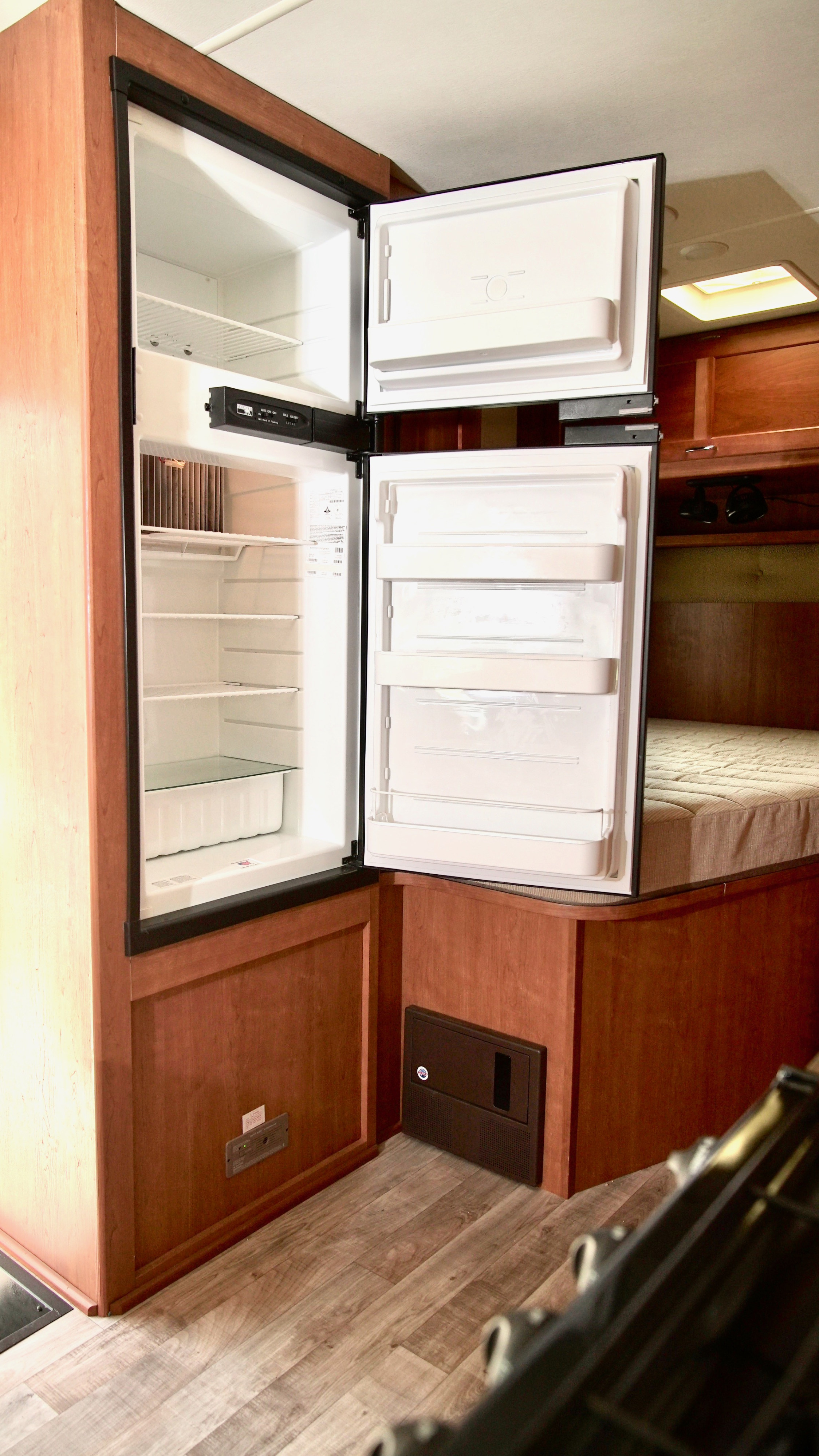 RV rental: An open, empty refrigerator and freezer unit within a clean, wood-finished RV interior.. Winnebago Minnie Winnie 2017