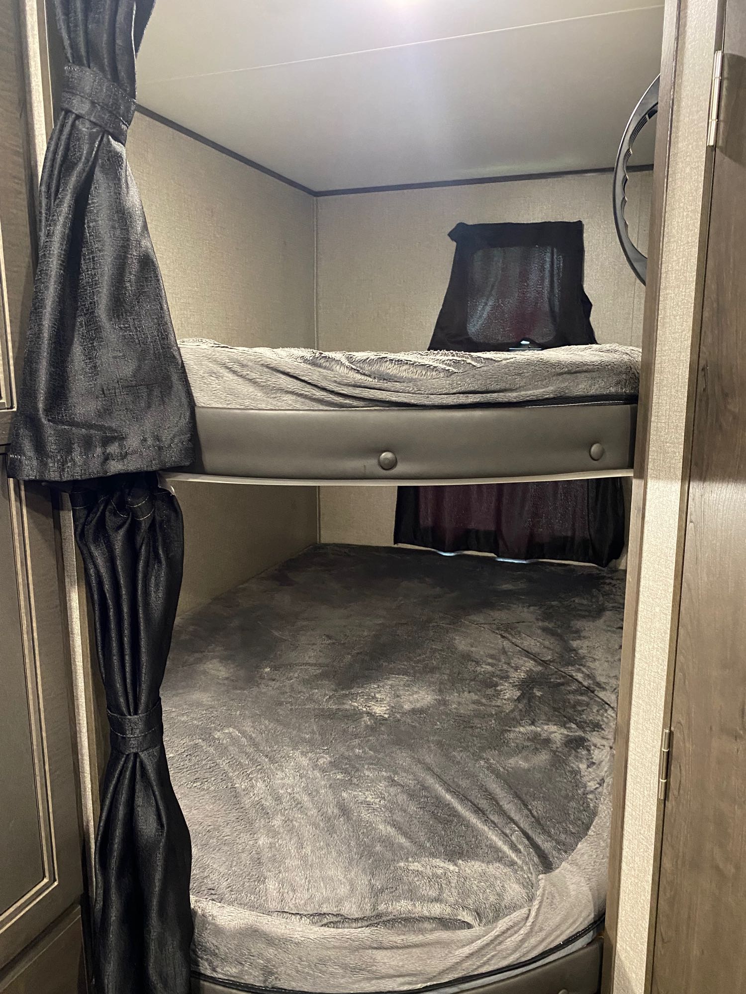 Cozy bunk beds in an RV rental, featuring dark privacy curtains and soft blankets for comfortable sleeping.. Jayco Jay Flight 2021