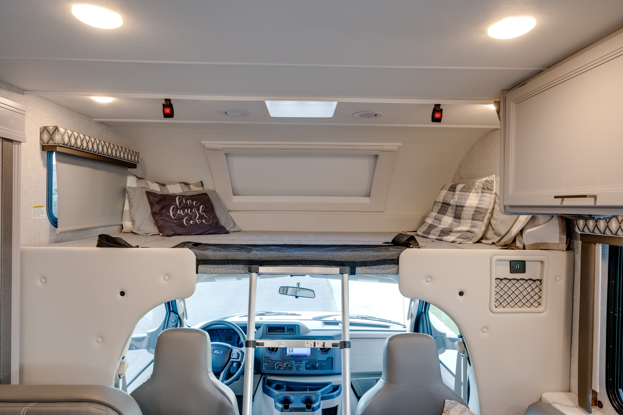 Overhead sleeping bunk and driver's cockpit of this spacious RV rental interior, ideal for comfortable travel.. Thor Geneva 2023