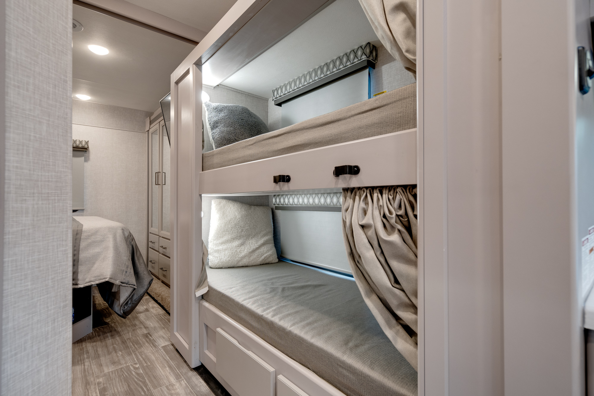 Step inside this RV rental's sleeping area, featuring cozy bunk beds with privacy curtains. A comfortable, compact space.. Thor Geneva 2023