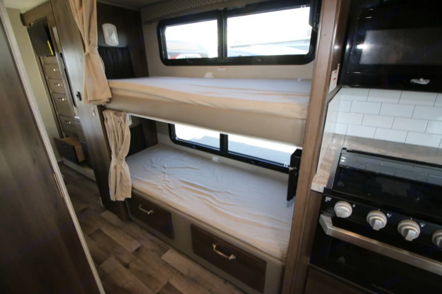 RV rental: Bunk beds with windows, built-in storage, and a compact kitchen with a microwave and stove in a modern RV interior.. Jayco Greyhawk 2019