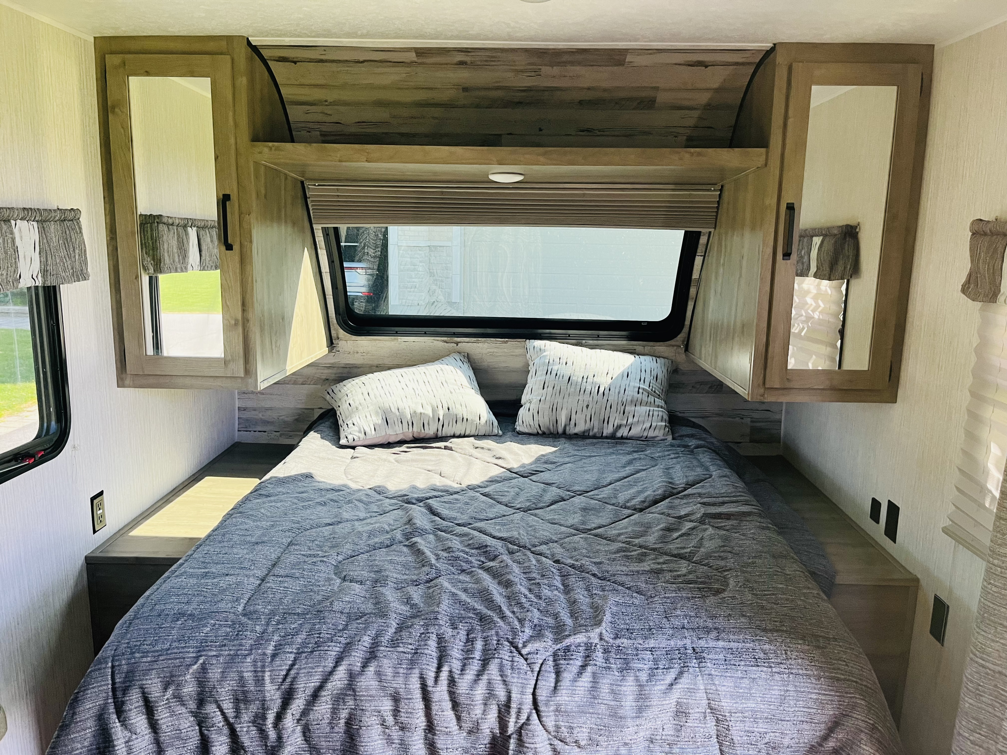 Inside an RV rental bedroom: A comfortable bed with pillows, overhead cabinets, and windows with blinds for a relaxing stay.. Palomino PUMA 22RBC 2022
