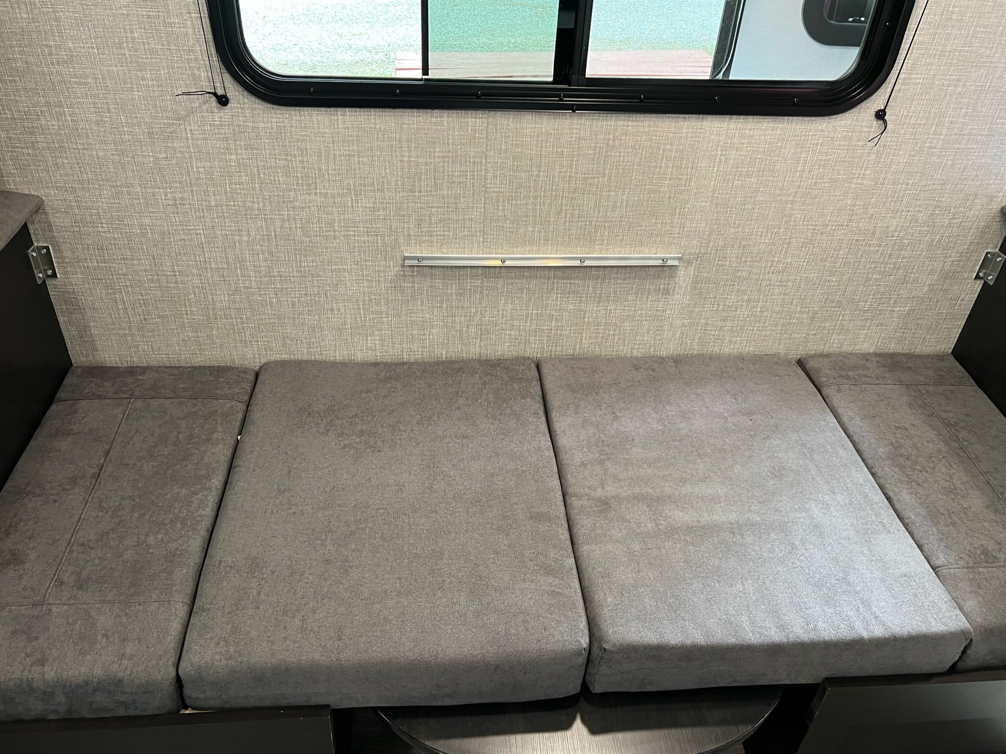 RV rental interior: grey dinette cushions convertible to bed, below window & wall rail.. Jayco Jay Flight SLX 2023