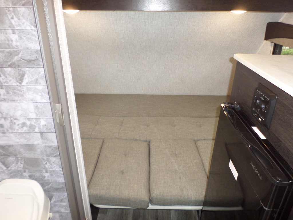 RV rental interior: convertible bed, compact kitchen with fridge & controls, plus a small toilet area for your adventures.. Braxton Creek Bushwhacker Plus 2022