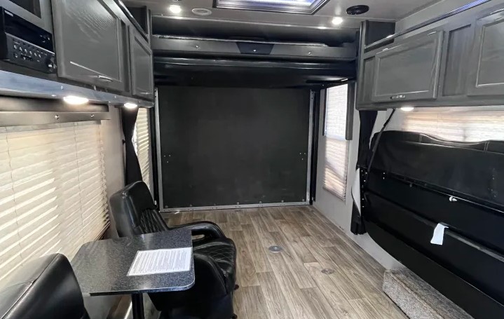 Spacious RV rental interior featuring a versatile toy hauler garage with convertible seating, perfect for cargo or living.. Genesis Supreme Rv Genesis Supreme 2019