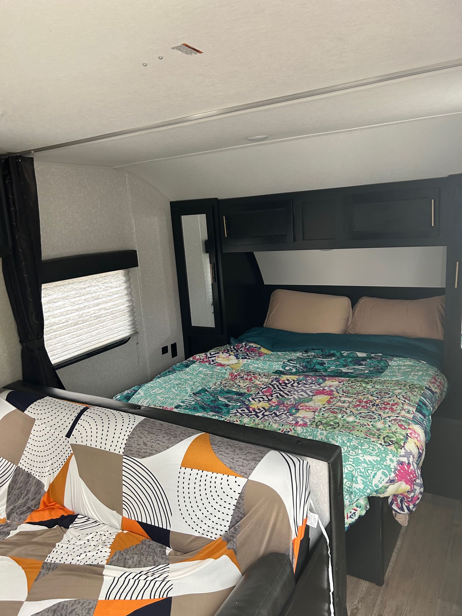 Spacious rv rental interior showcasing a cozy bedroom with colorful bedding and a patterned living area for comfortable travel.. Forest River Cherokee Grey Wolf Special Edition 2022