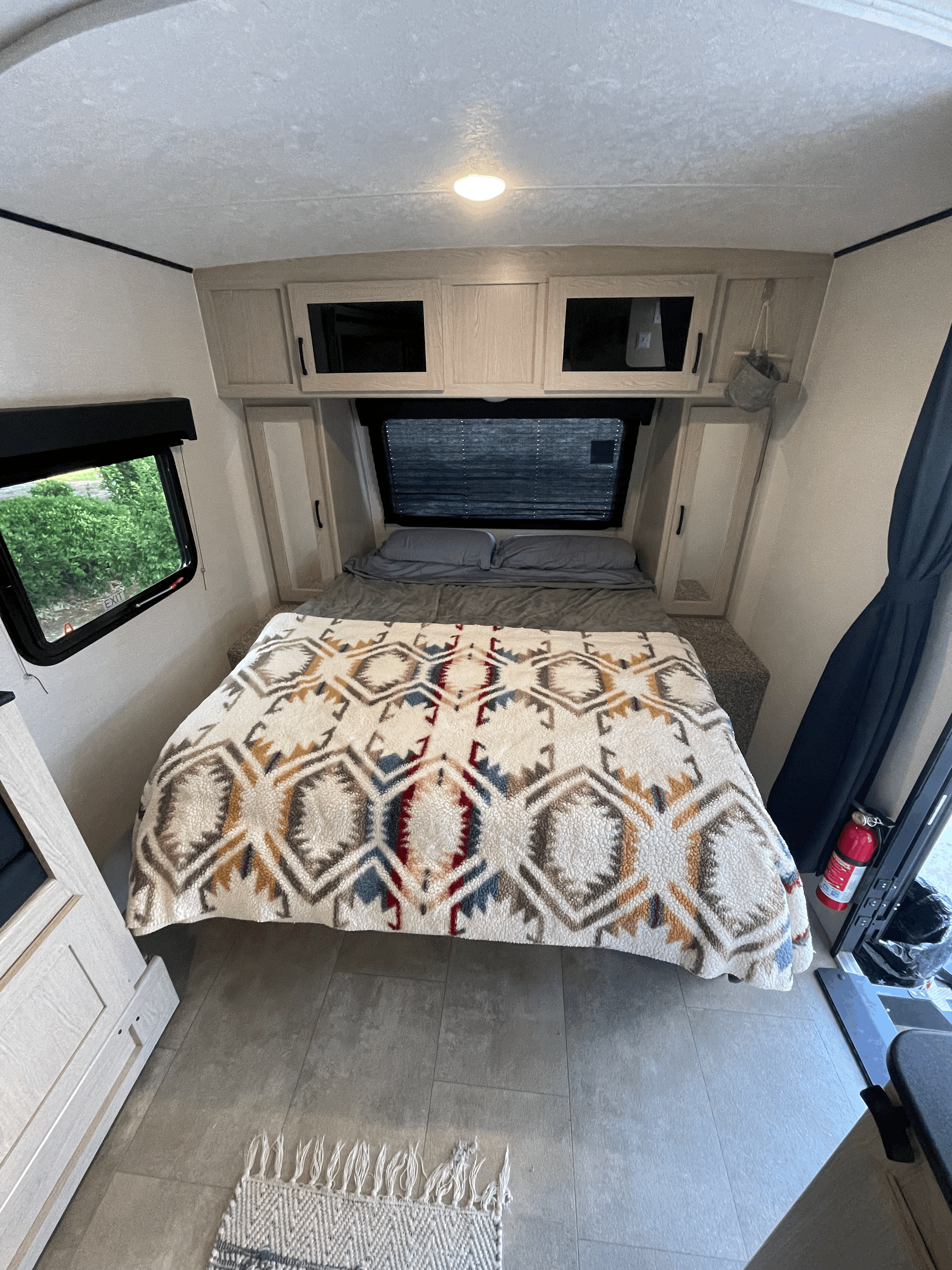 Cozy RV rental bedroom with patterned blanket, overhead storage, and windows for a comfortable stay.. Coachmen Apex Nano 2021