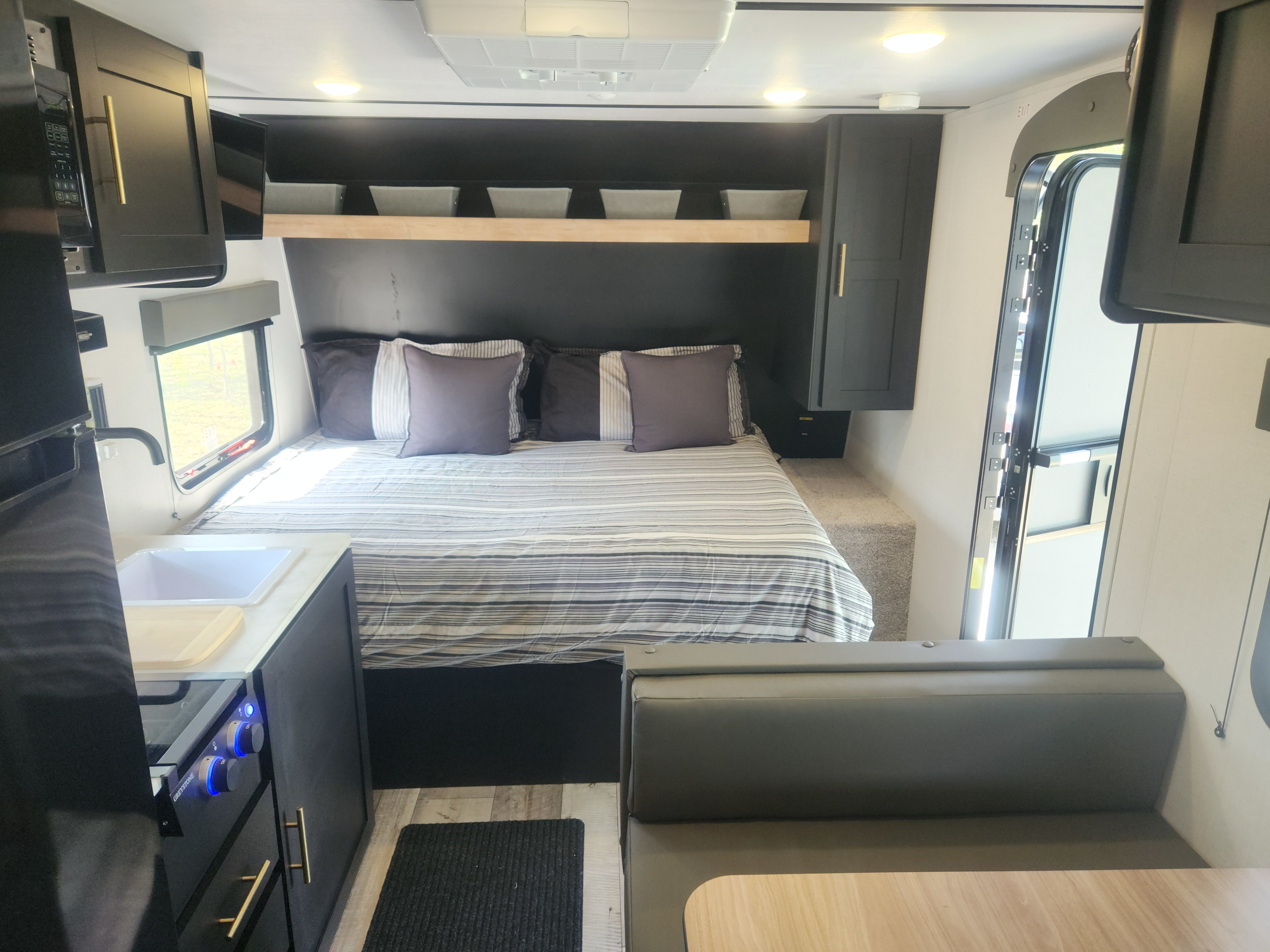Cozy RV rental interior with a bed, overhead storage, small kitchen, and dinette.. Keystone RV Springdale 2023