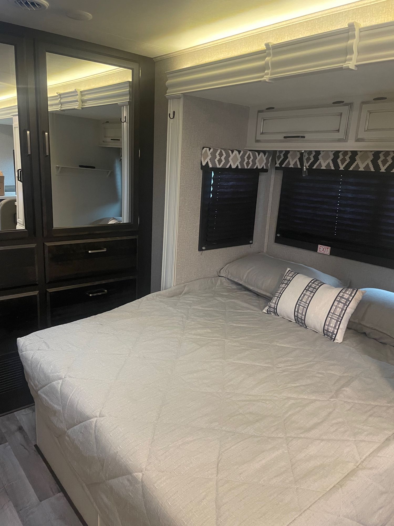 Experience comfort in this well-appointed RV rental bedroom, featuring a large bed, mirrored wardrobe, and overhead storage.. Entegra Coach Odyssey 2021