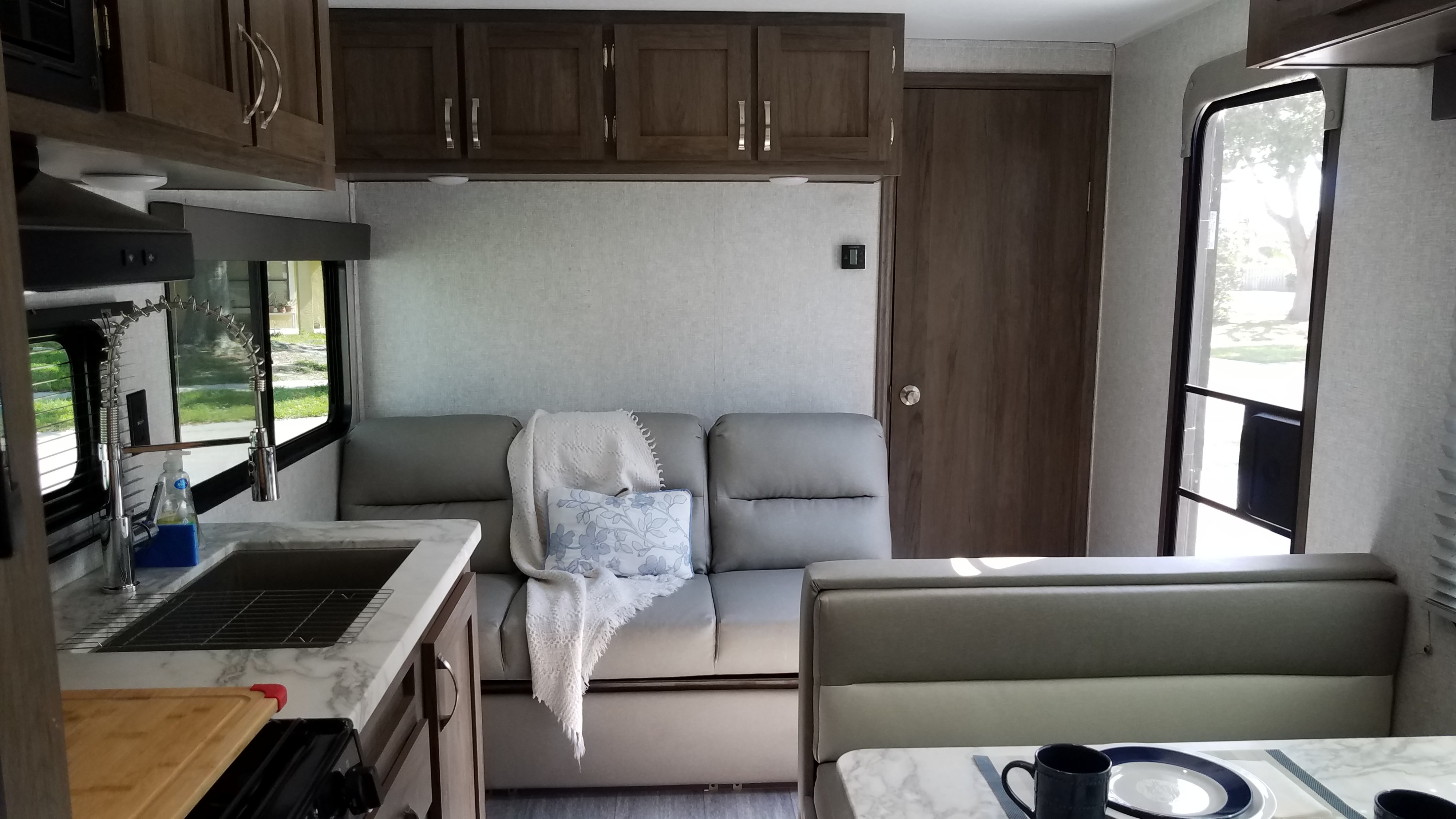 This RV rental offers a bright, complete interior: kitchen with sink, comfy sofa, and dinette for travel comfort.. East to West Silver Lake 2021
