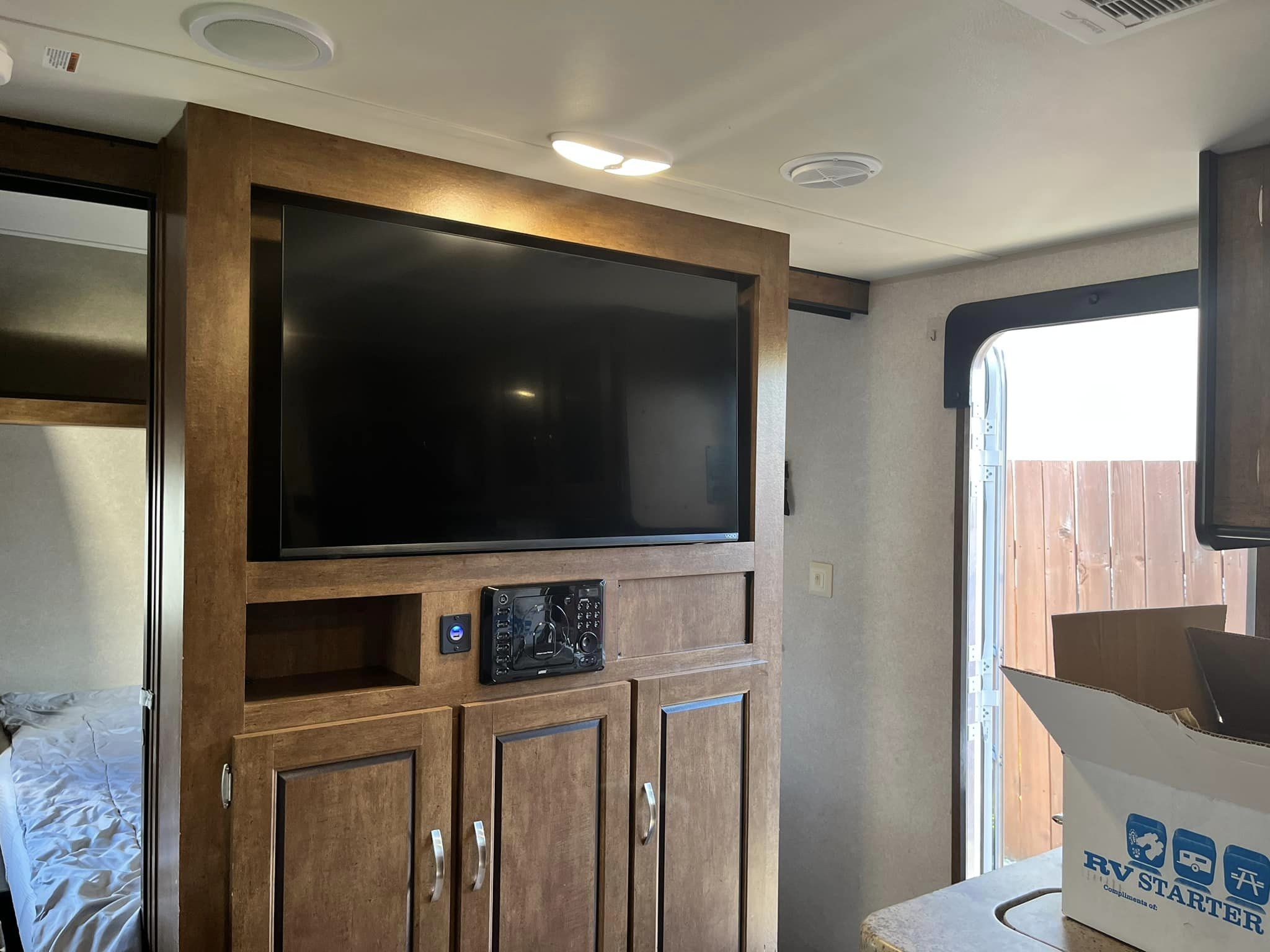 Modern rv rental interior showing a large TV, sound system, and sleeping area. Entry door open to outside.. Forest River Salem Cruise Lite 2017