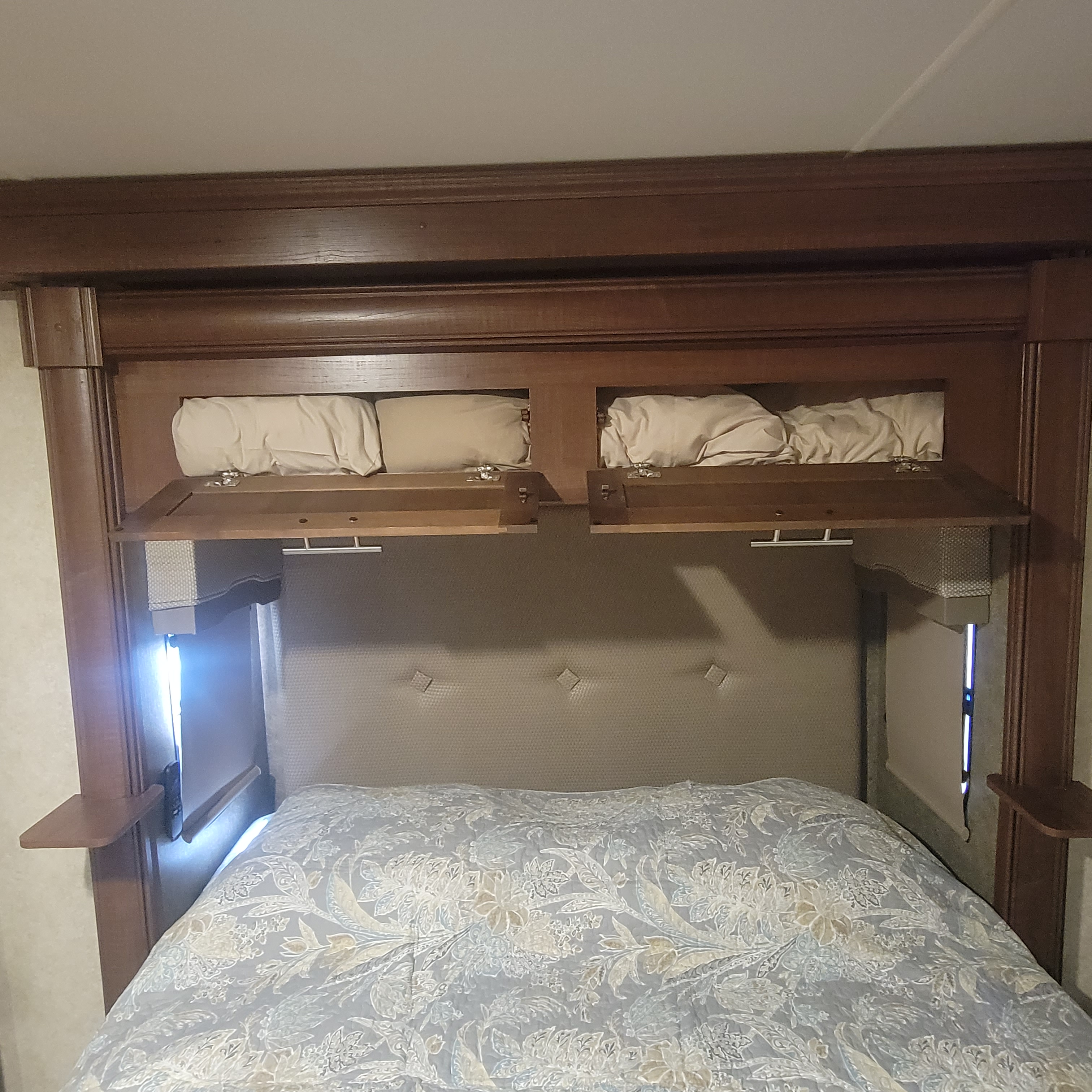 Cozy RV rental bedroom featuring practical overhead storage, a padded headboard, and comfortable, patterned bedding.. Georgetown GT5 2017