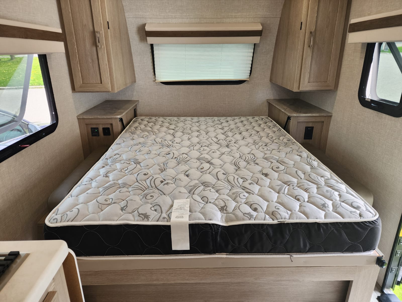 Spacious RV rental bedroom featuring a comfortable bed, overhead cabinets, and side shelves, ideal for your next adventure.. Forest River Rockwood Geo Pro 2022