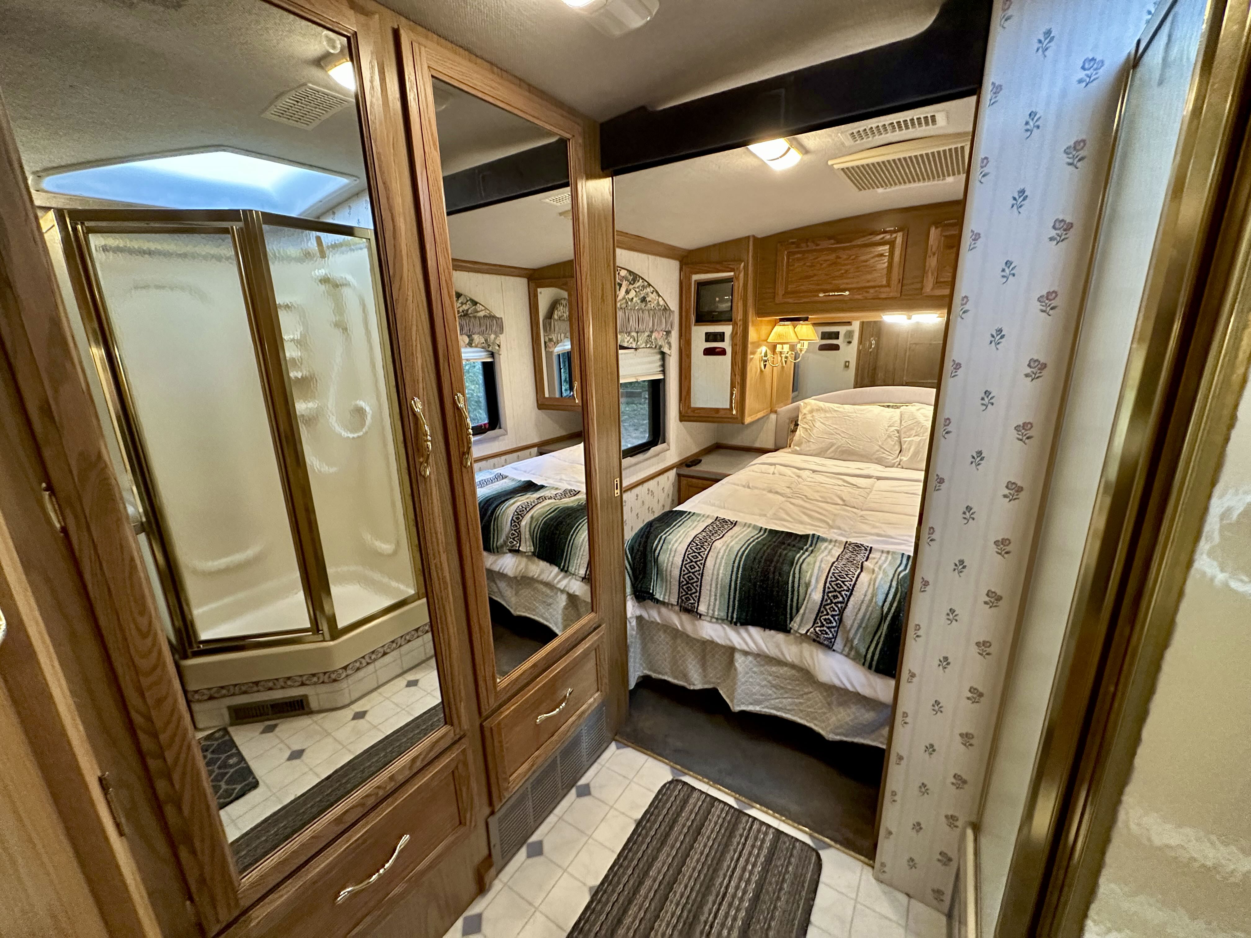 This RV rental's spacious interior offers a comfortable bedroom, full shower, and charming details reflected in cabinet mirrors.. Fleetwood Pace Arrow 1997