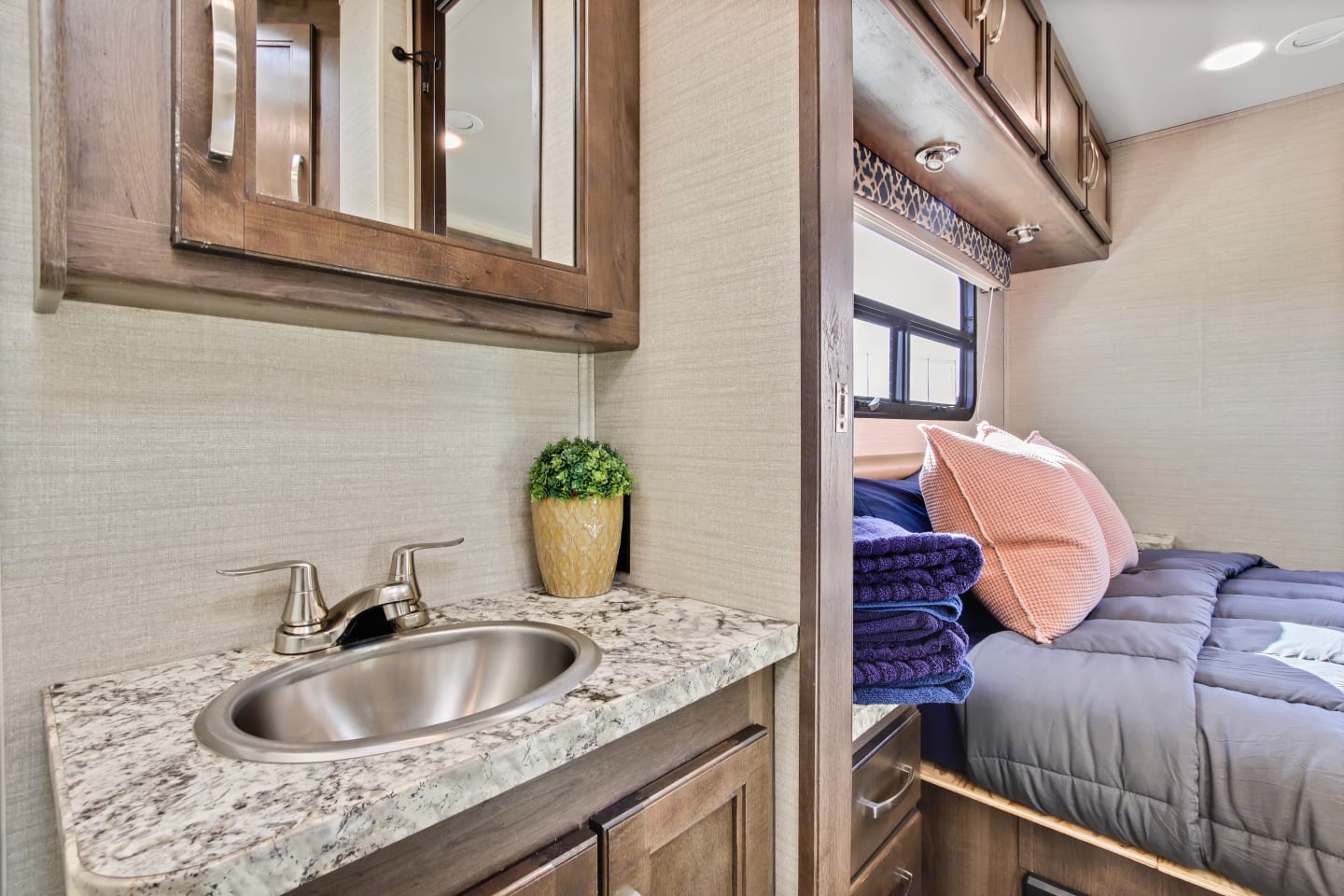 Inside an RV rental: a compact bathroom vanity with sink and mirror, leading to a cozy bedroom.. Jayco Redhawk 2019