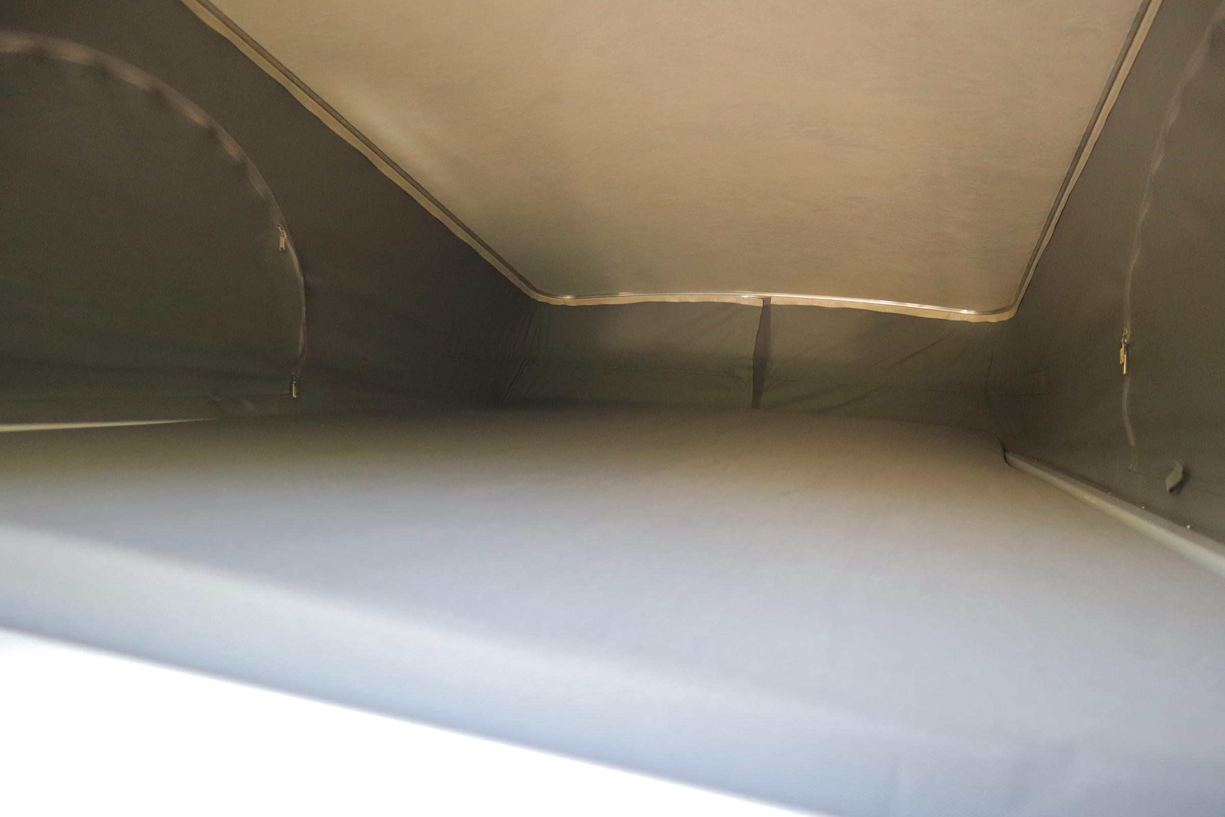 RV rental's pop-top interior. A light upper sleeping platform and dark fabric tent walls with visible zippers.. Winnebago Solis 2021