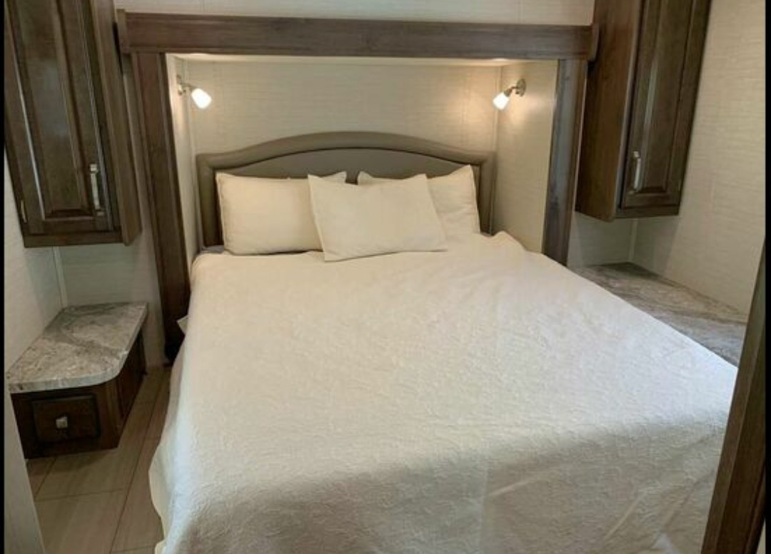 Comfortable RV rental bedroom with queen bed, overhead cabinets, and reading lights. Ideal for a relaxing trip.. Jayco Greyhawk 2018