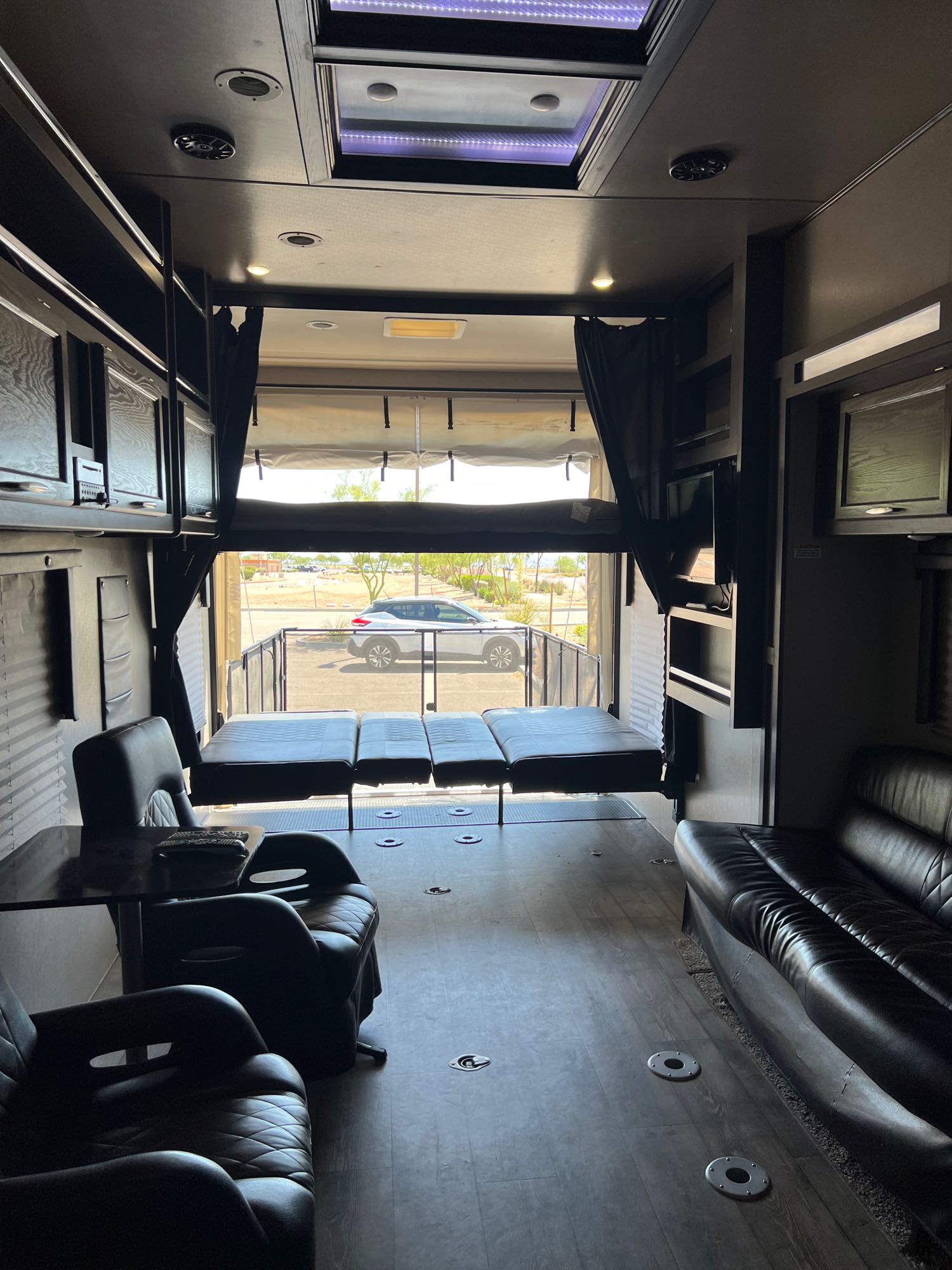Spacious RV rental toy hauler interior with ramp open, revealing outdoor view. Features living area, beds, and garage.. Genesis Supreme Rv Genesis Supreme 2020