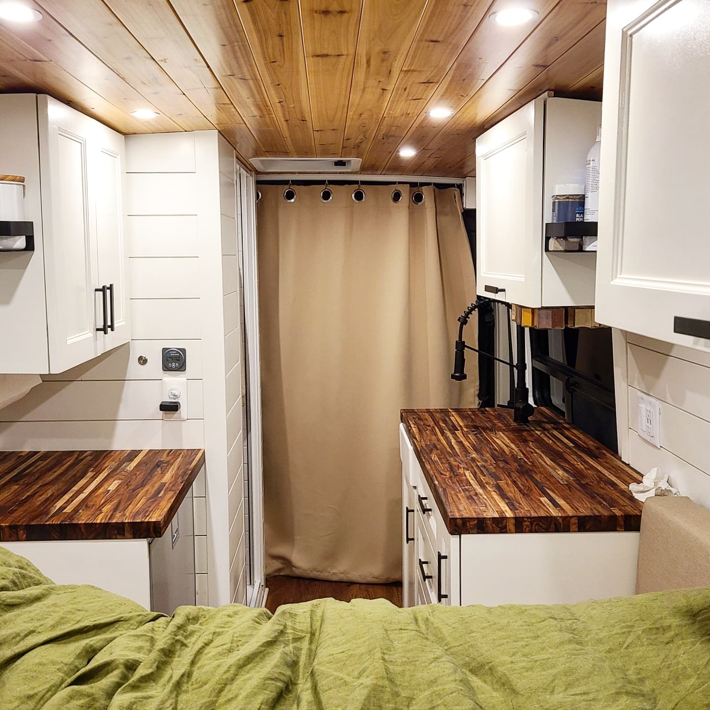 Bright RV rental interior with wood ceiling, white cabinetry, and warm wood counters. Features an integrated shower and inviting green bed.. Dodge RAM 3500 Promaster 159" Extended 2019