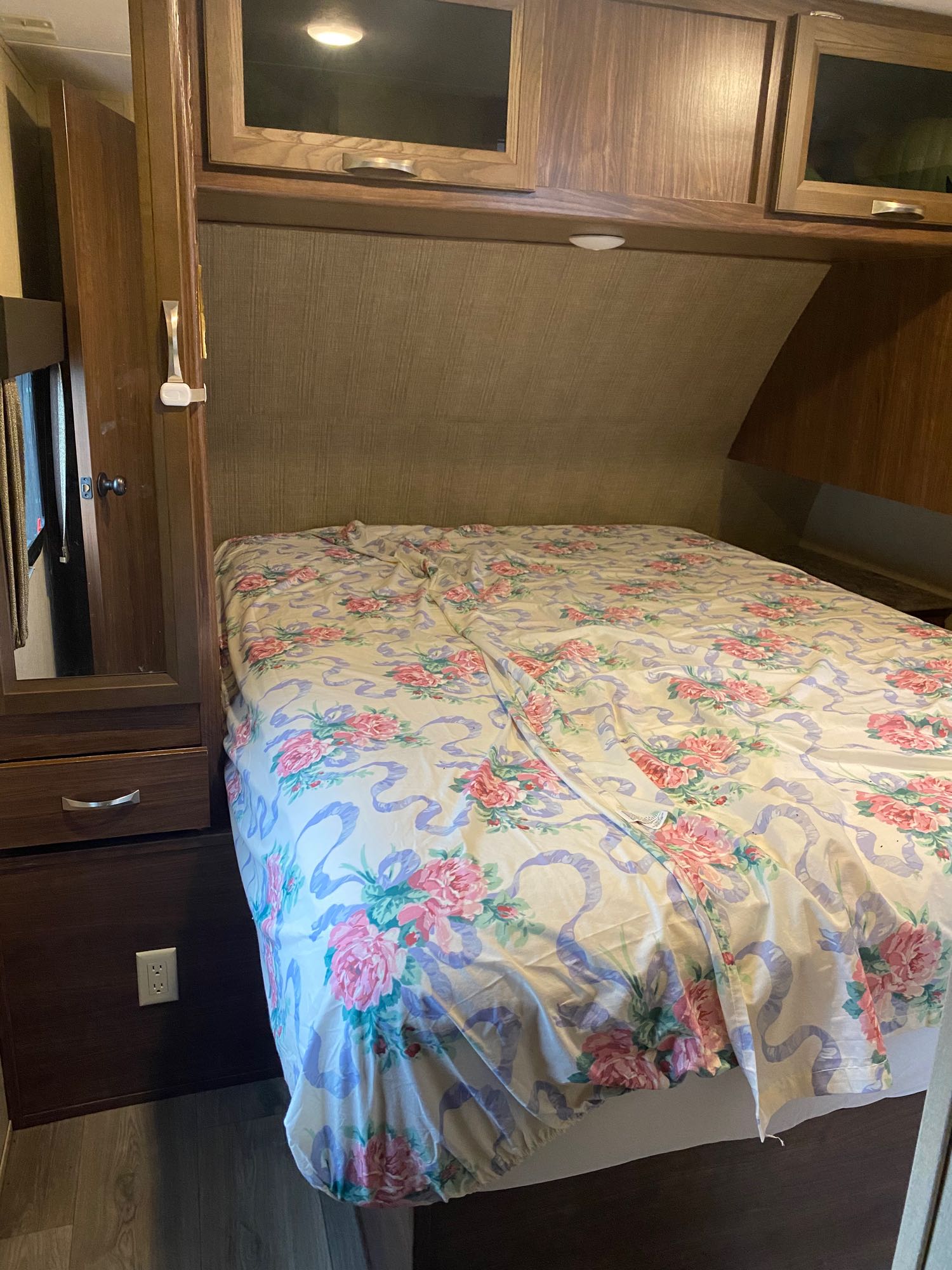 RV rental: a compact bedroom features a bed with floral bedding, wooden cabinets, and storage.. Coleman 2605 light 2017
