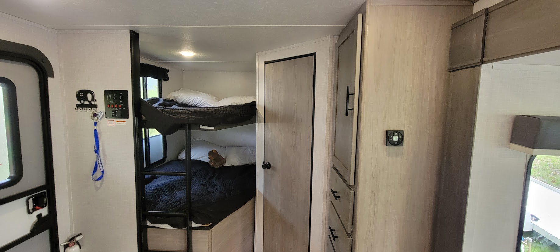 Inside a modern RV rental, featuring cozy bunk beds, a control panel, and storage for family travel comfort.. Dutchmen Coleman Light 2022