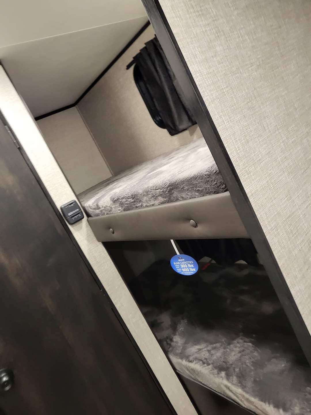 Inside an RV rental: comfortable stacked bunk beds for travel, showing a tag with 300 lbs (upper) and 600 lbs (lower) capacity.. Jayco Jay Flight SLX 2022