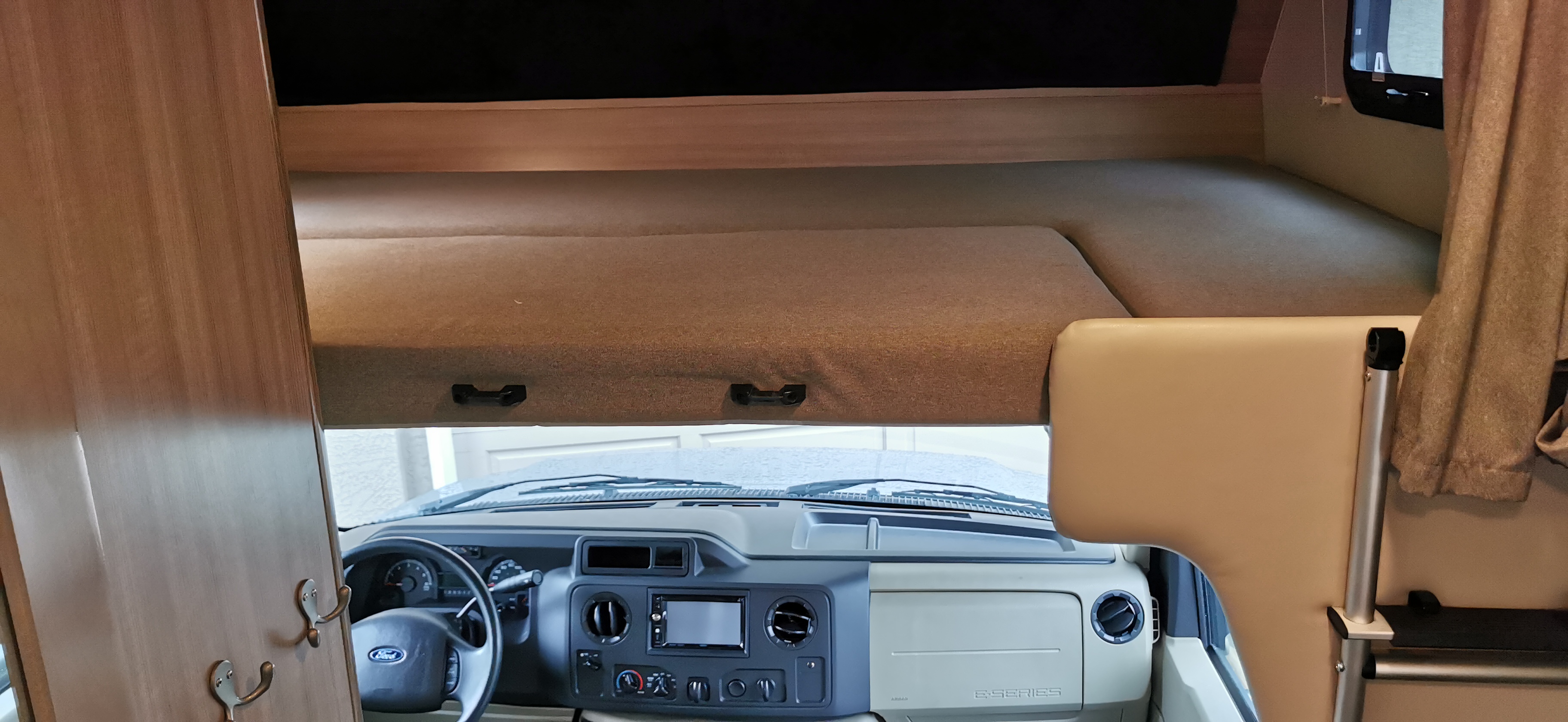RV rental interior: View of the comfortable cab-over bunk above the Ford E-Series dashboard.. Ford Adventure 2021