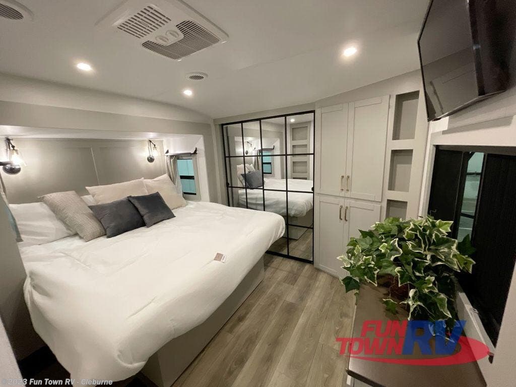 Spacious RV rental bedroom with a large bed, built-in storage, wall-mounted TV, and a stylish glass partition. Modern comfort for travelers.. Brinkley Z 3100 2024