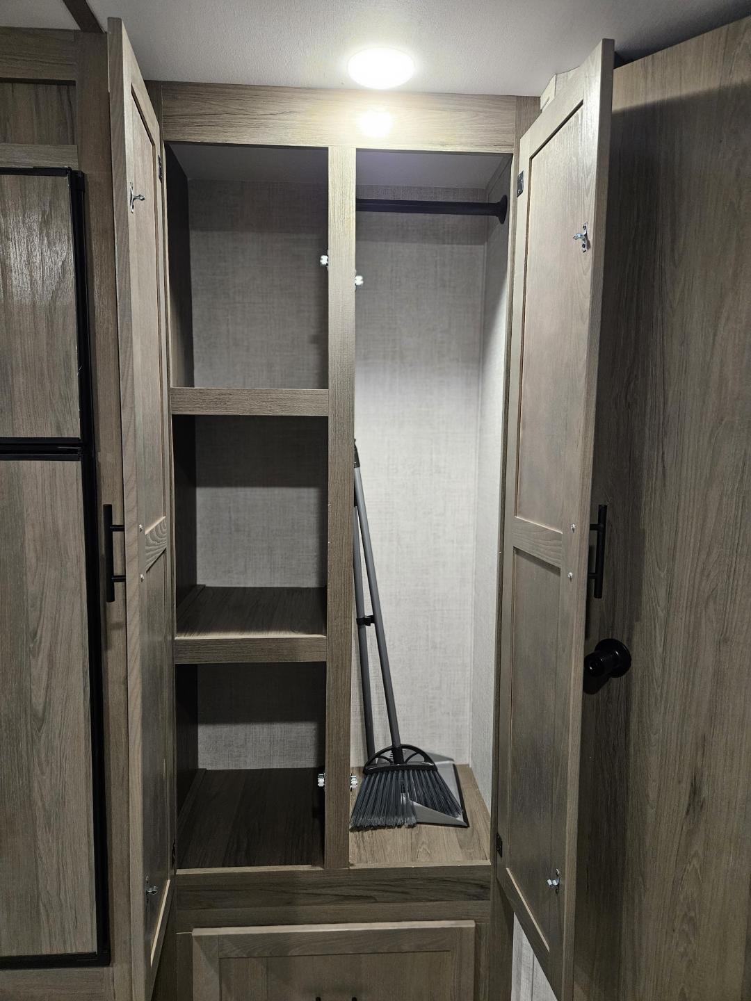 Inside an RV rental: versatile storage cabinet with shelves, a hanging rod, and a broom for your travels.. Gulf Stream Ameri-Lite 2022