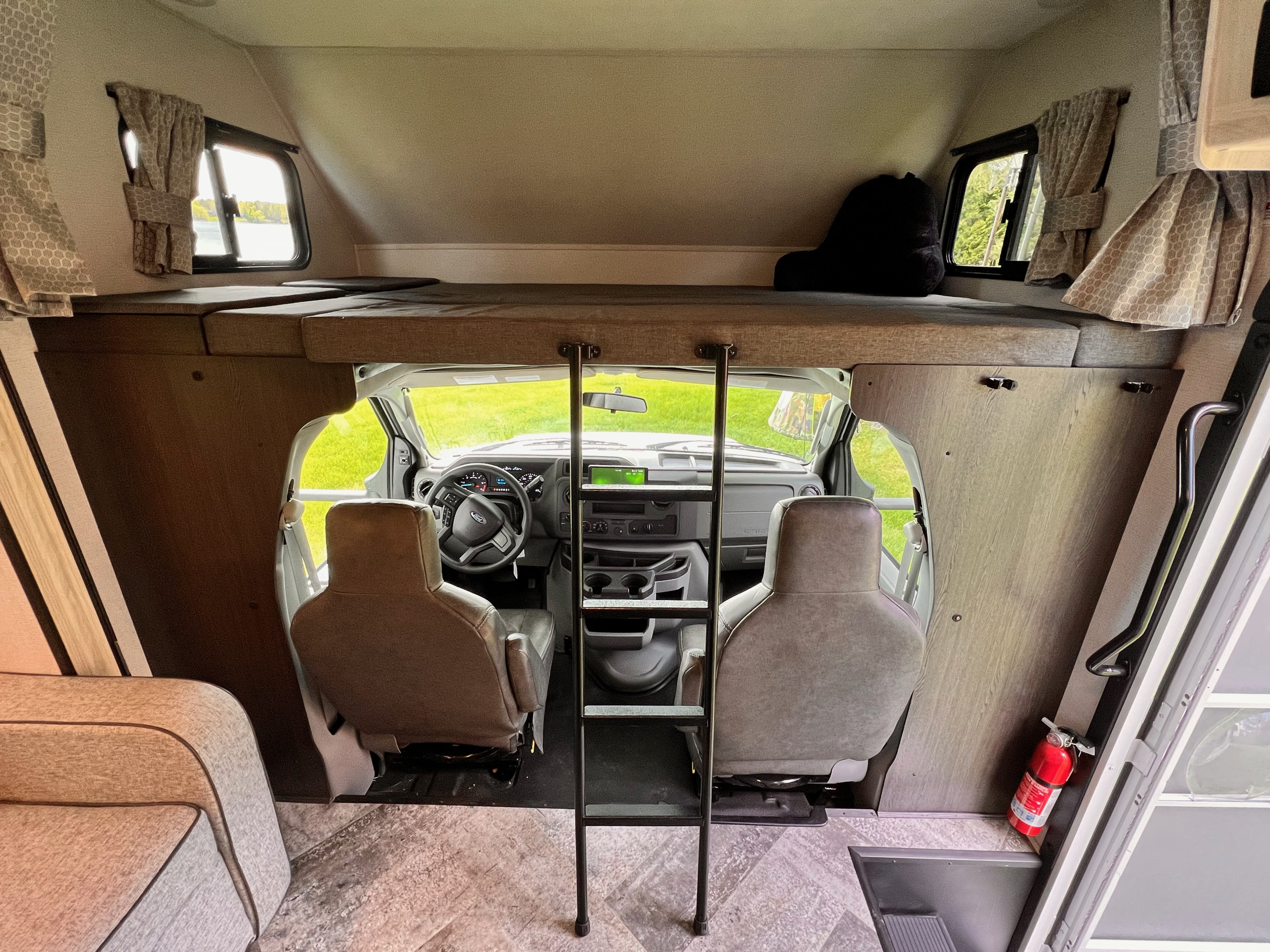 Inside an rv rental, showing the driver's cab, a comfy over-cab bunk bed with ladder. Ready for adventure!. Forest River Sunseeker Classic 2021