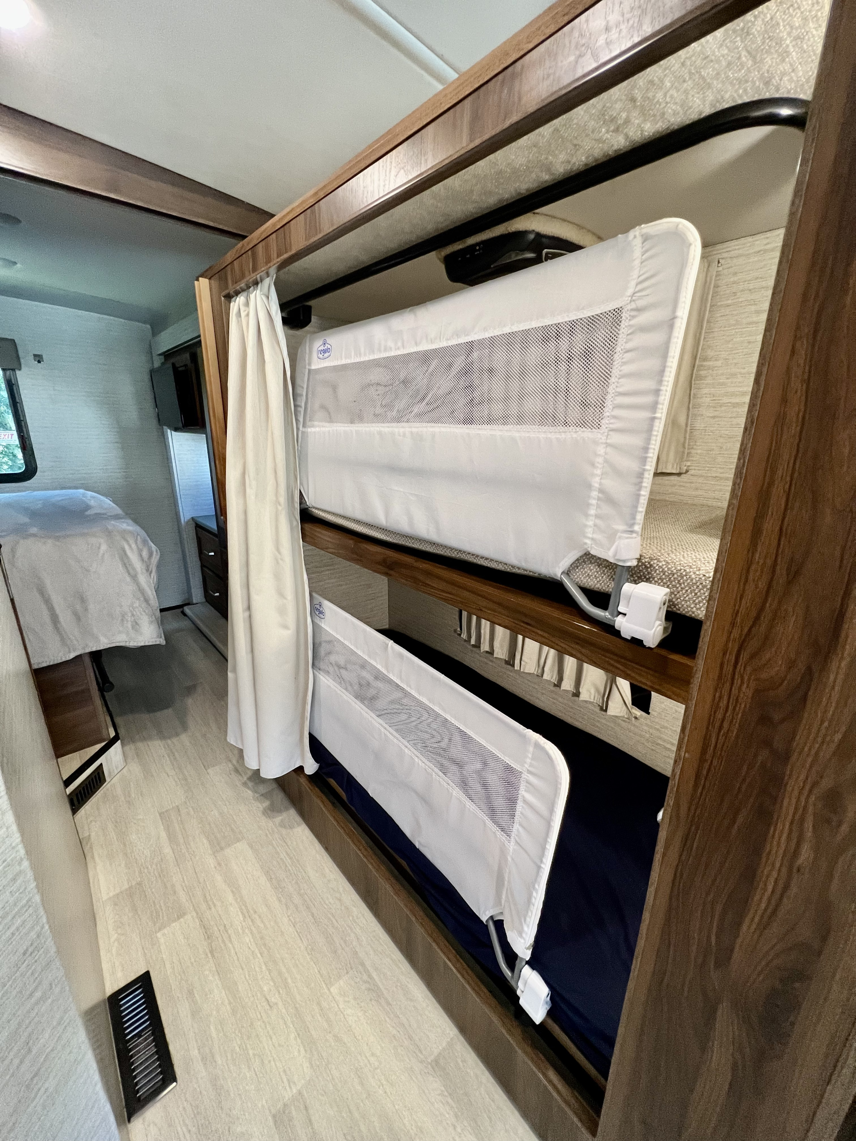 RV rental interior features secure bunk beds with safety rails and privacy curtain, ideal for families.. Winnebago Vista 2021